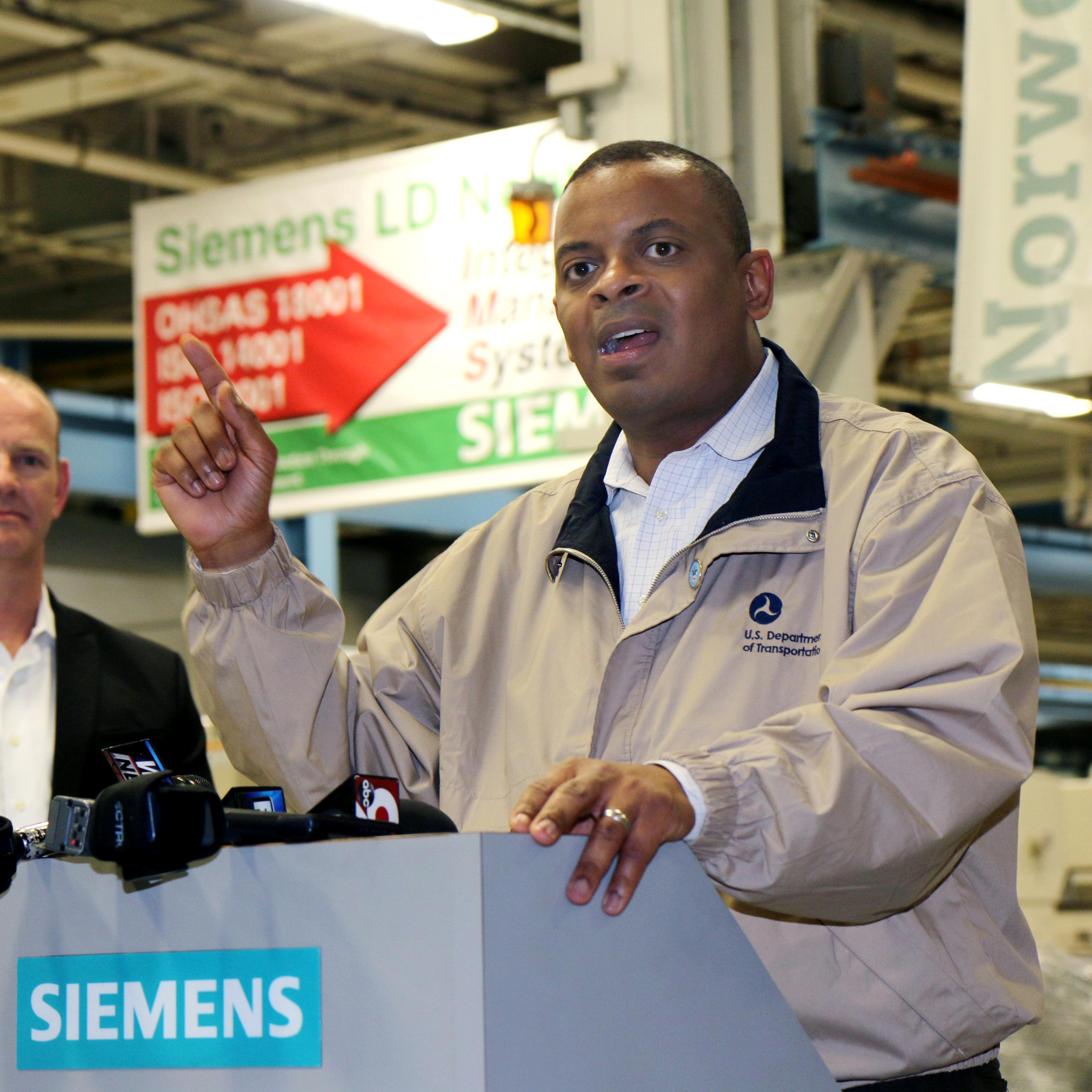 From left: Michael Cahill, President of Siemens Rail Systems in the U.S. listens to U.S. Transportation Secretary Anthony Foxx at the Siemens Motors Manufacturing Plant in Norwood, Ohio, April 14, 2014.