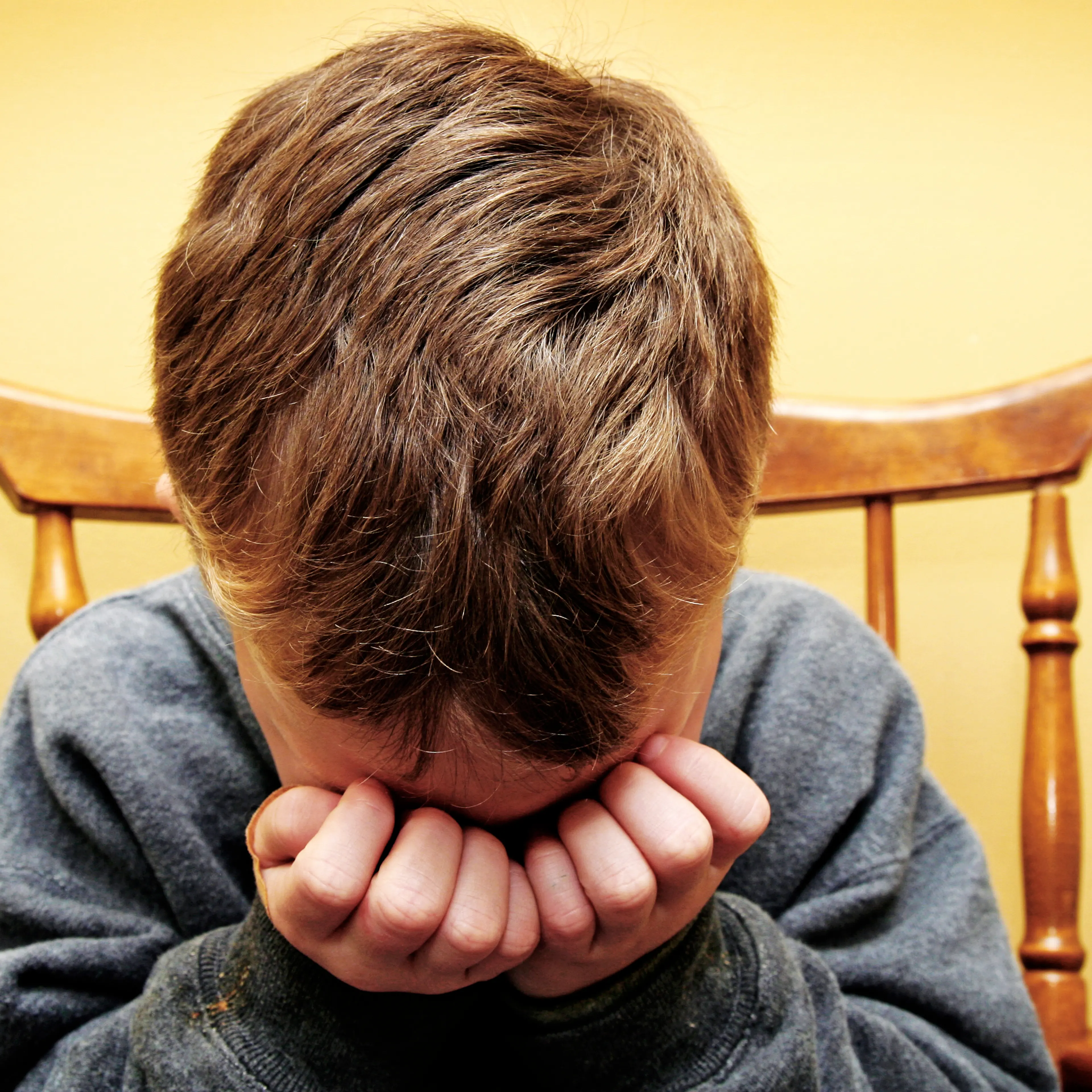 Young Boy Hides His Face In Tears
