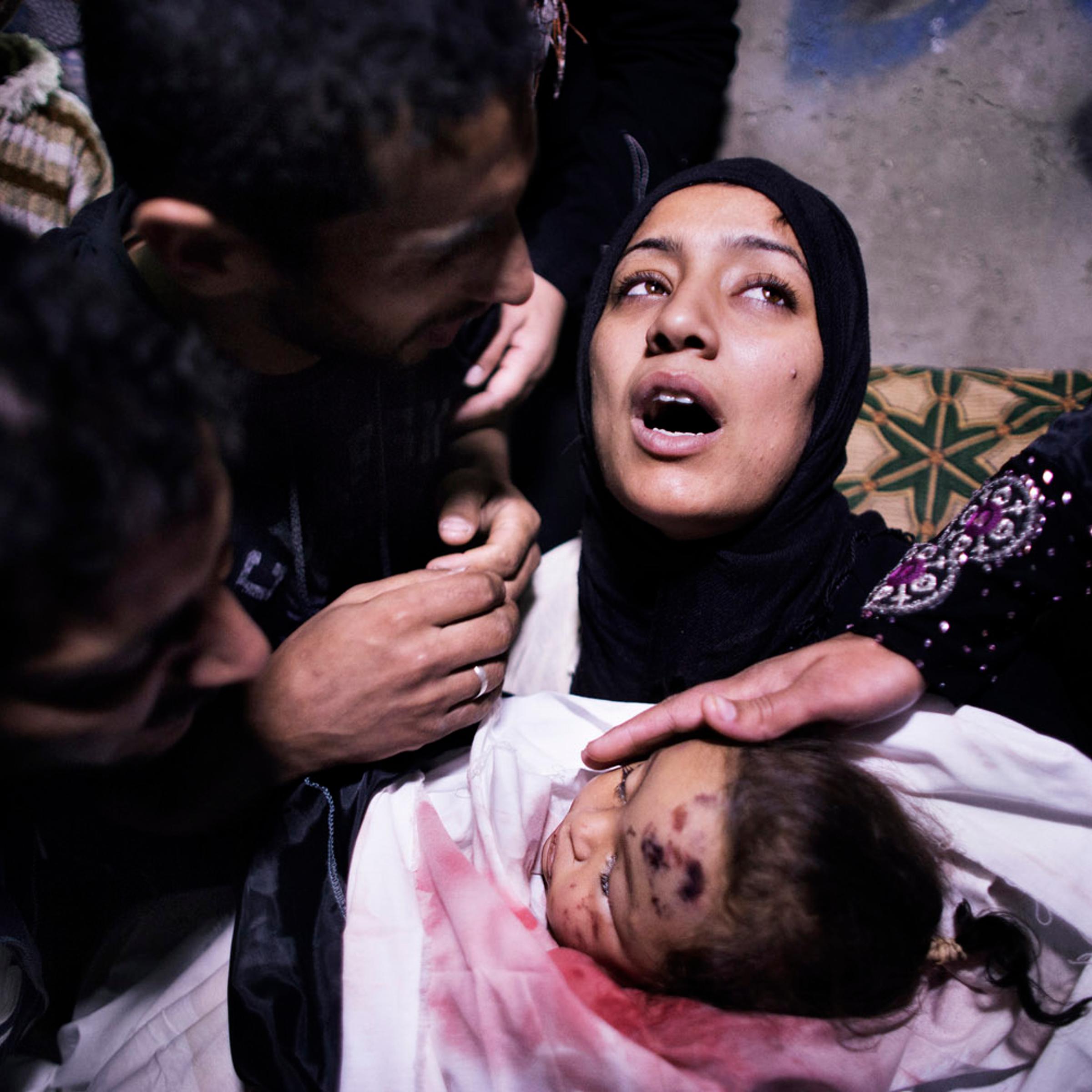 Nov. 16, 2012. The mother of a 10-month-old Palestinian girl killed the day before in an Israeli air strike is comforted by her husband and relatives as she mourns before her daughter's funeral in Gaza City.