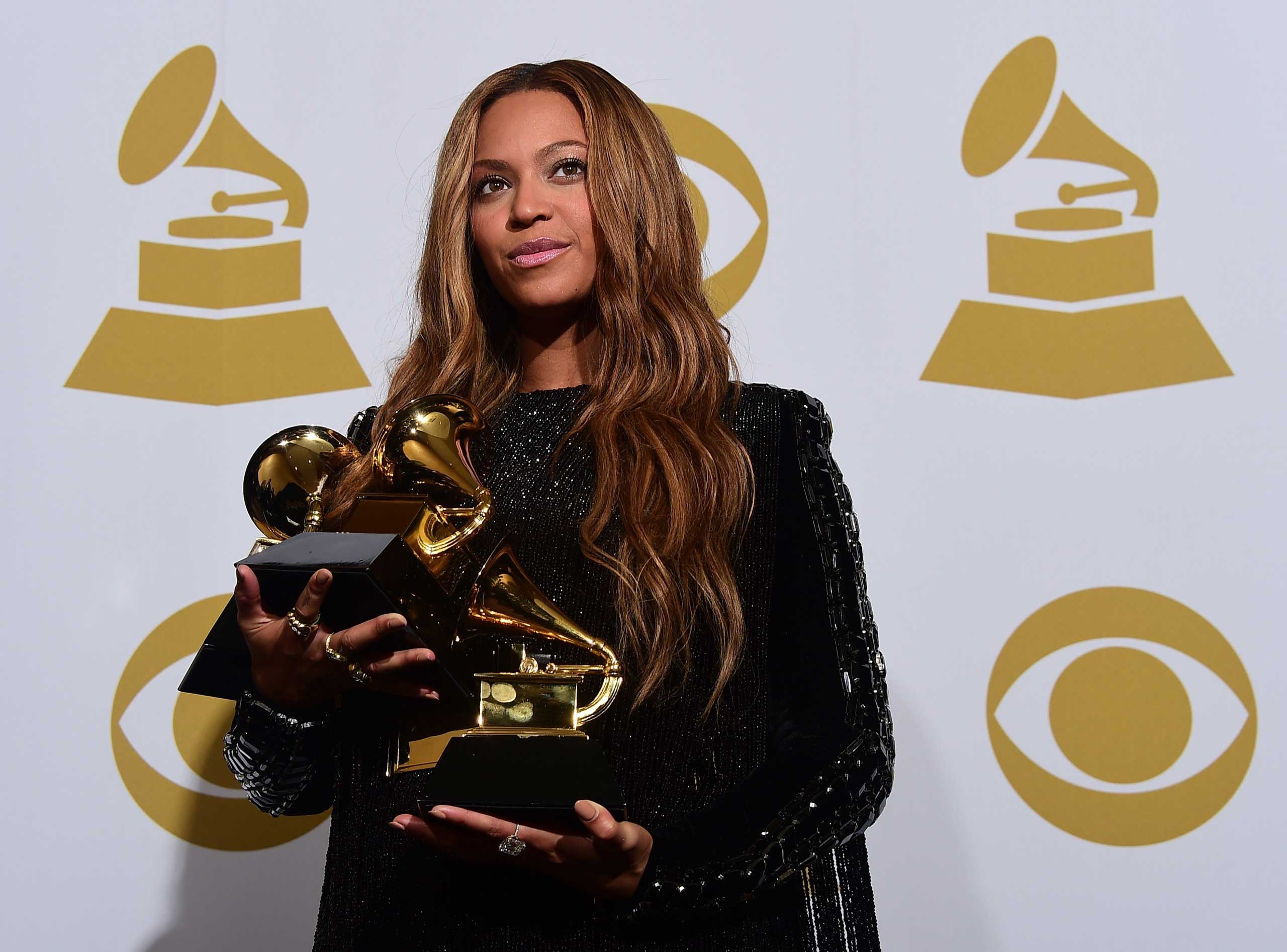 Beyonce poses with her three Grammys in the press room during the 57th annual Grammy Awards in Los Angeles, Feb. 8, 2015.