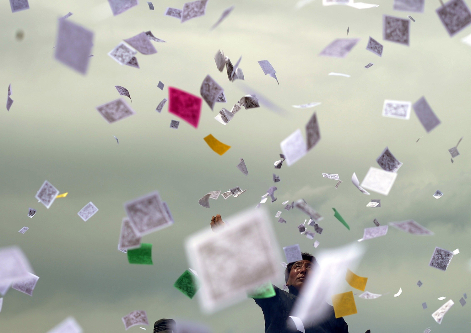 A Tibetan throws pieces of prayer paper know as longda, into the air as they gather to celebrate the wei sang festival, in Hongyuan China on June 18, 2014