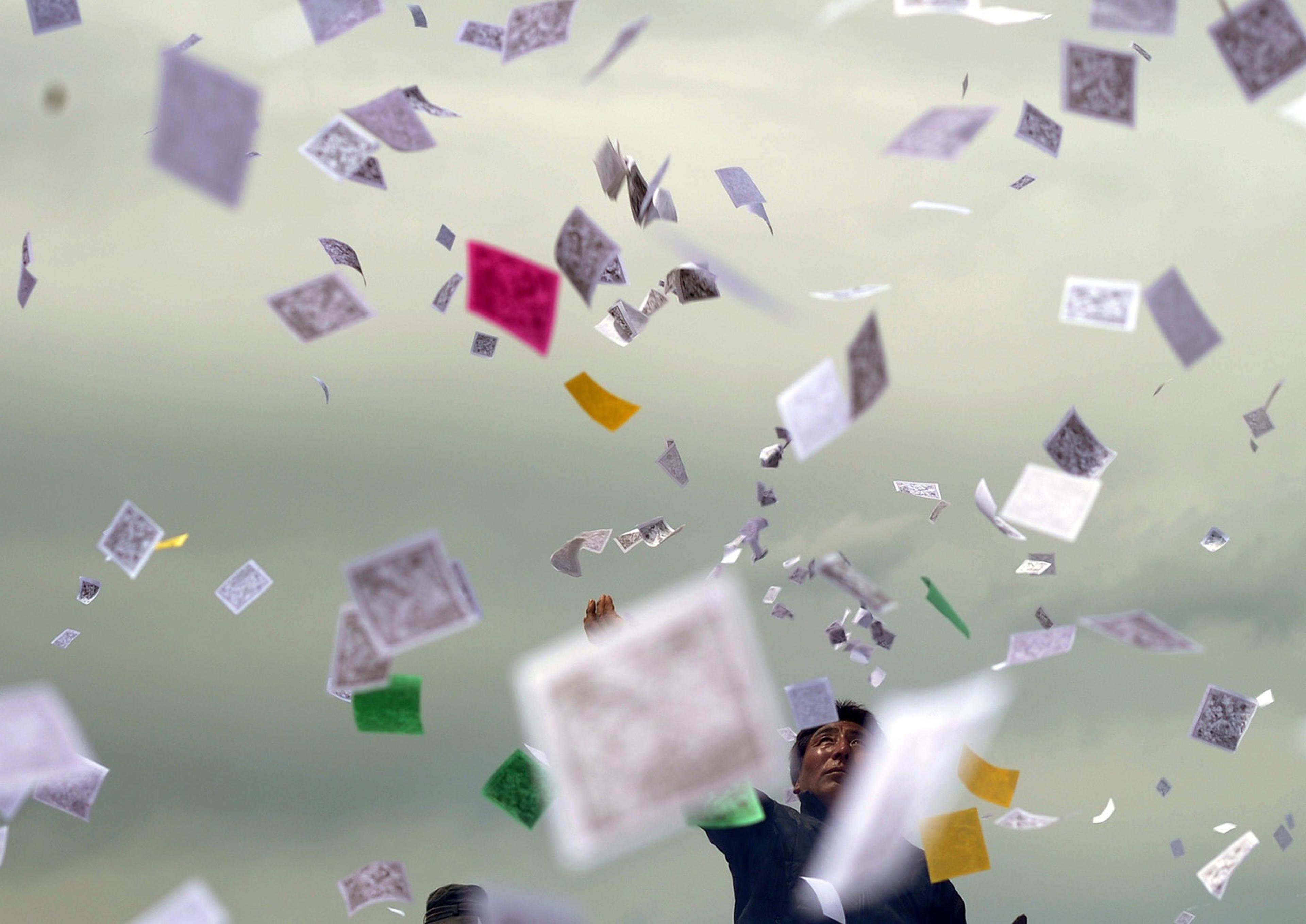 A Tibetan throws pieces of prayer paper know as longda, into the air as they gather to celebrate the wei sang festival, in Hongyuan China on June 18, 2014