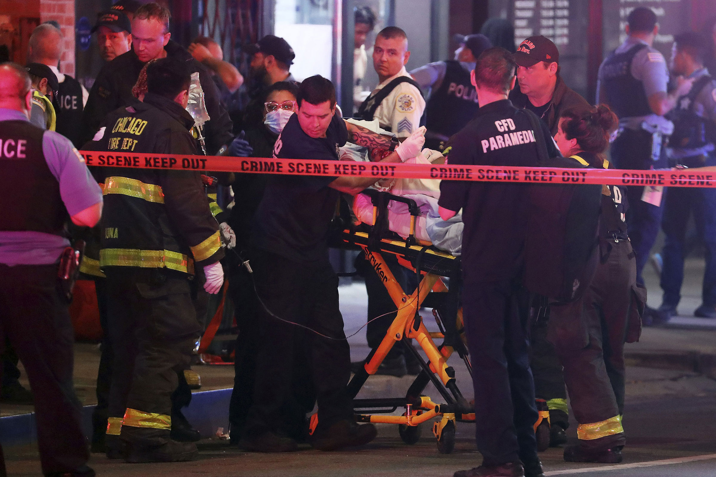 First responders move a shooting victim to an ambulance in downtown Chicago, May 14, 2022. A teenage boy was shot and killed near the sculpture Cloud Gate in Millennium Park.
