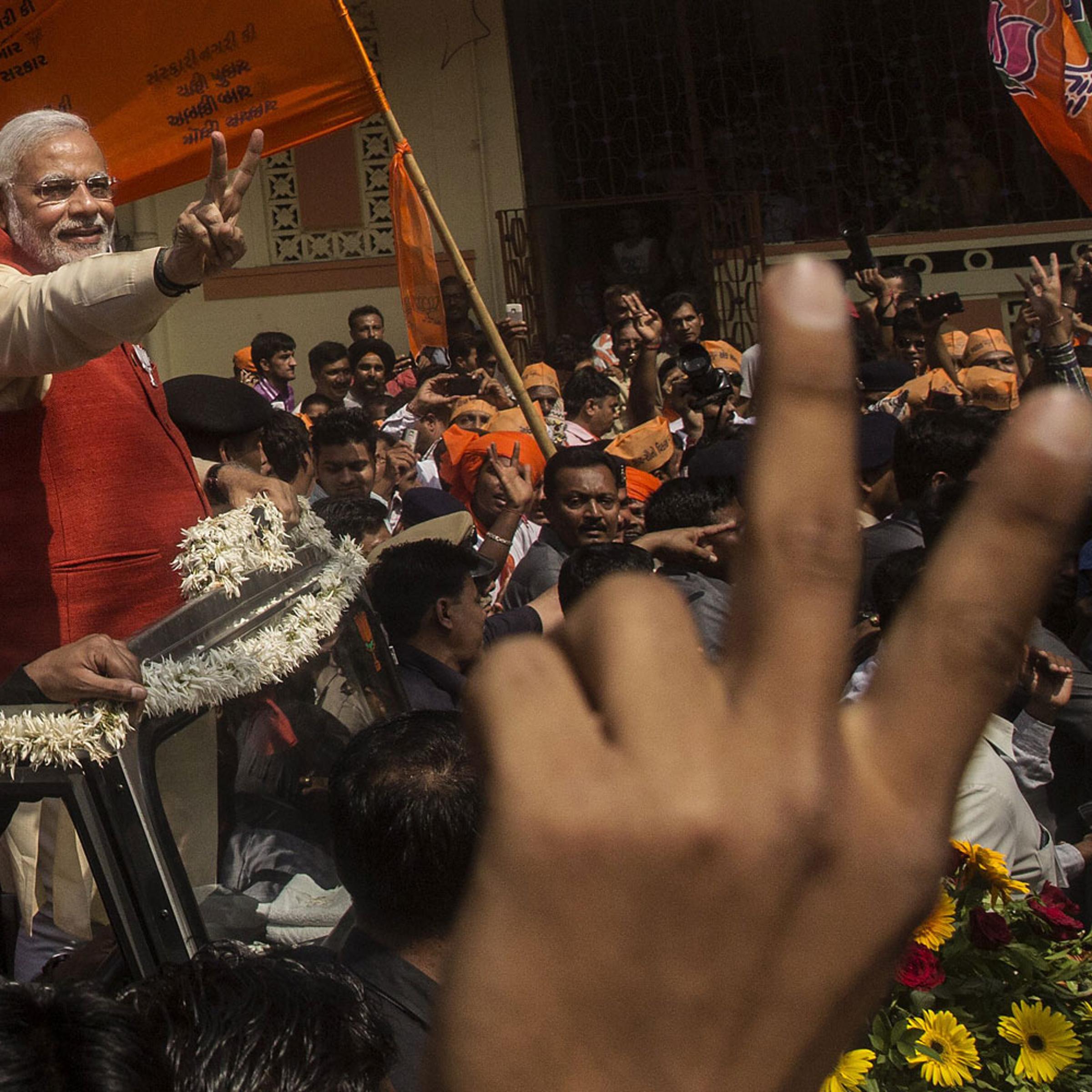 Bharatiya Janata Party leader Narendra Modi gestures to supporters as he rides in an open jeep on his way to file nomination papers on April 9, 2014 in Vadodra, India.