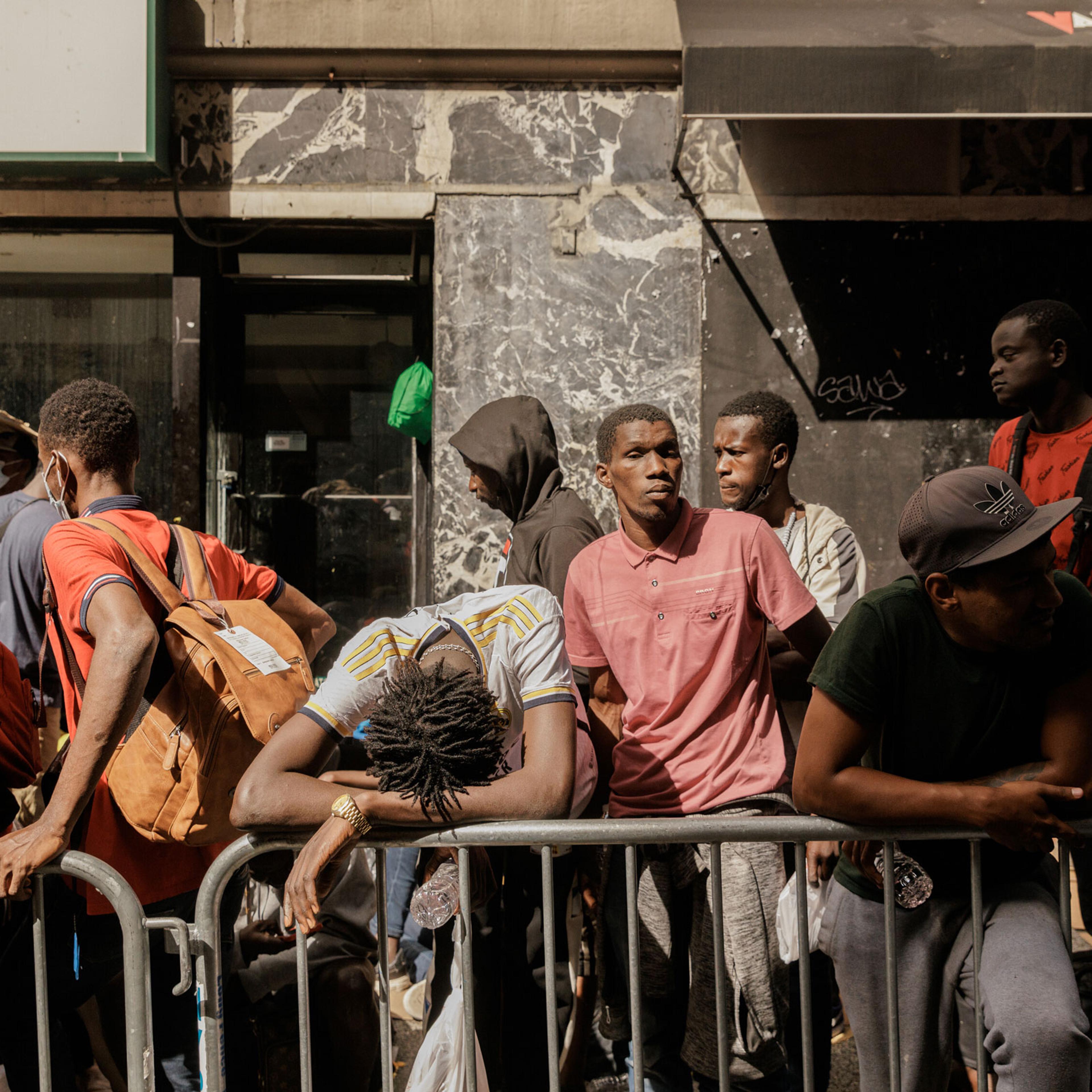 Migrants waiting to be processed queue outside of the Roosevelt Hotel
