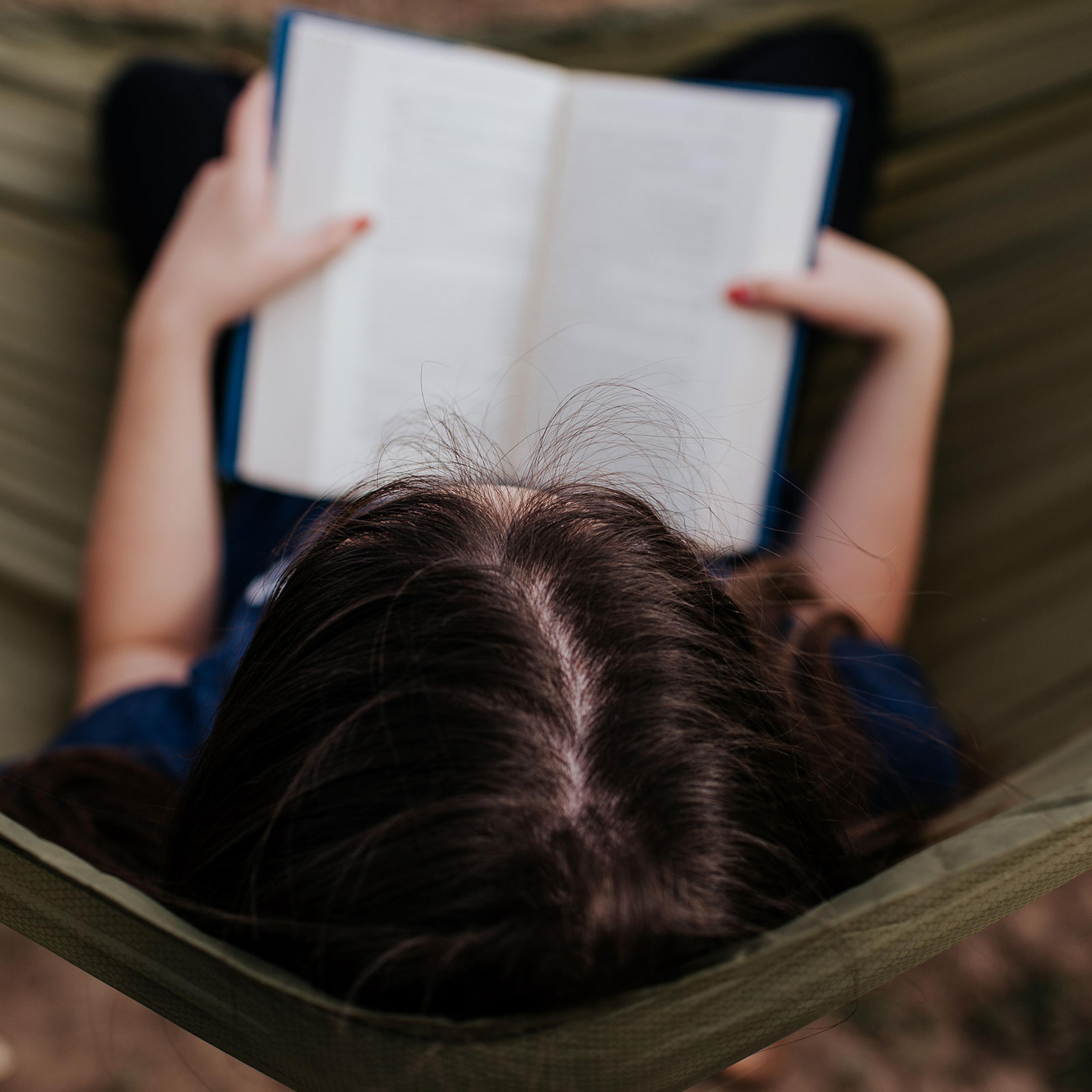 Center overhead frame of teen girl reading in hammock