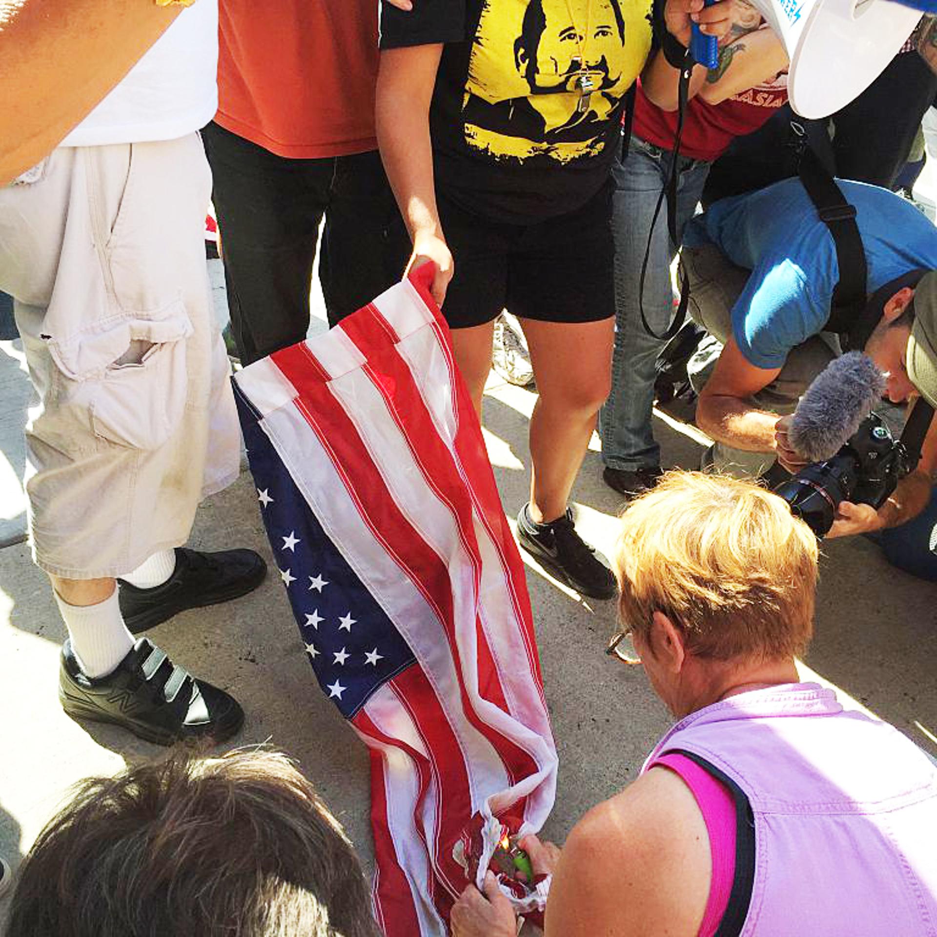 Anti-Trump protesters try to burn US flag during a rally outside the Republican National Convention in Cleveland, Ohio on July 20, 2016.