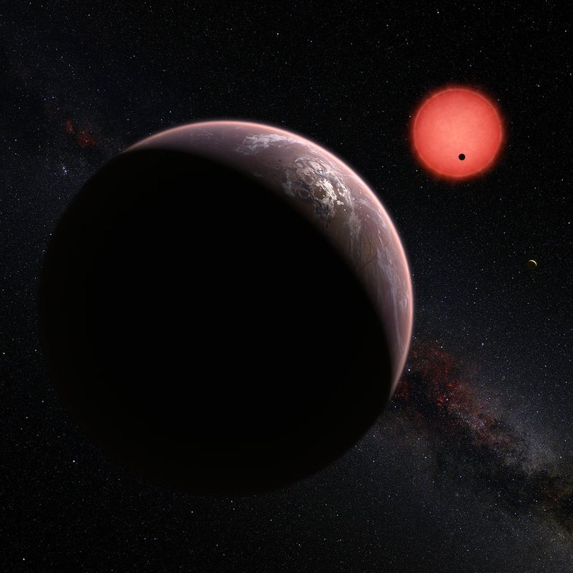 An artist’s impression of three of the seven planets orbiting Trappist-1. One planet is in the foreground; the other is a small silhouette as it transits the red dwarf star; the third is a tiny crescent off to the right.