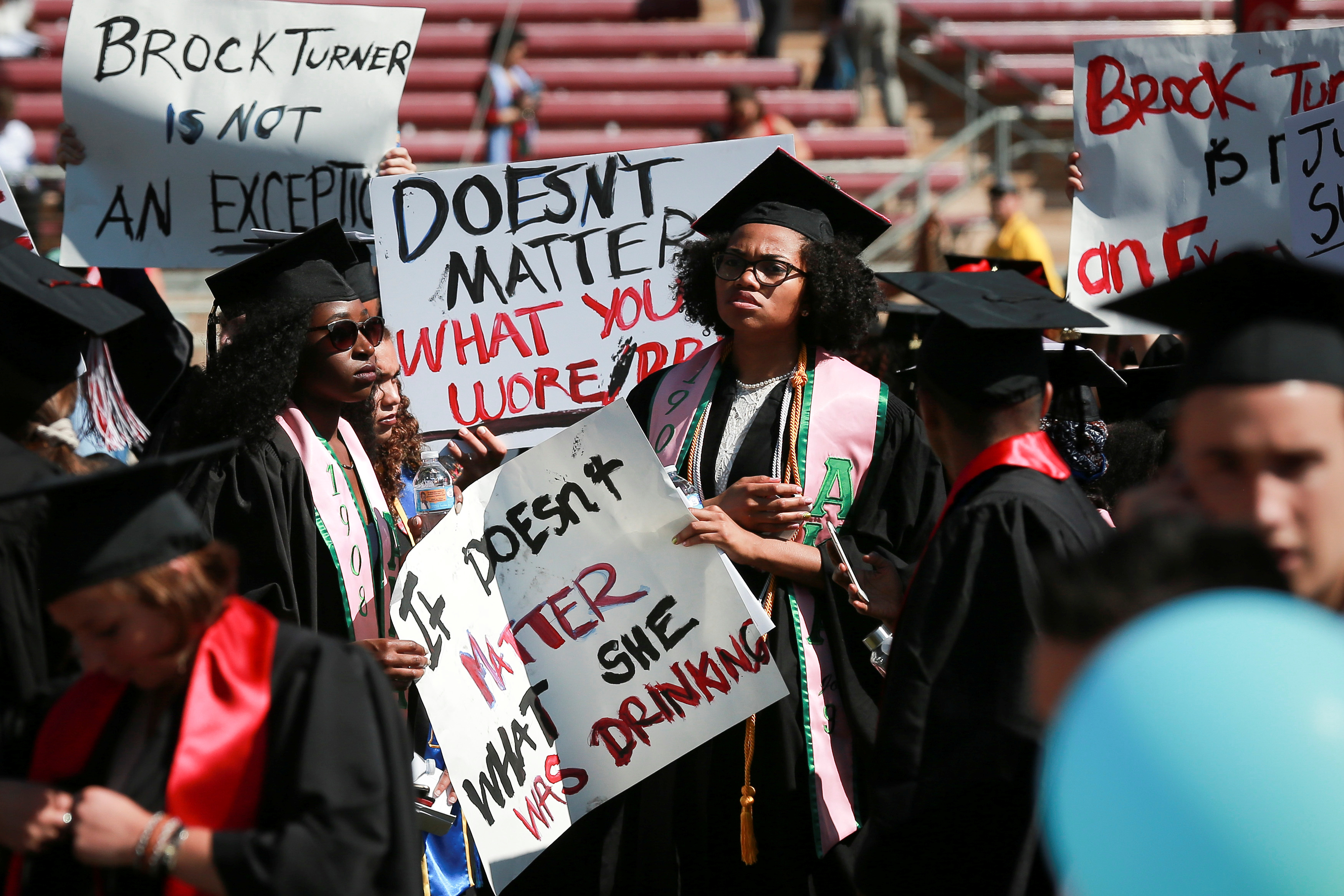 Protesters hold signs to raise awareness of sexual assault on campus in the wake of the national attention brought by the Stanford rape case at the Stanford University commencement ceremony in Palo Alto, California