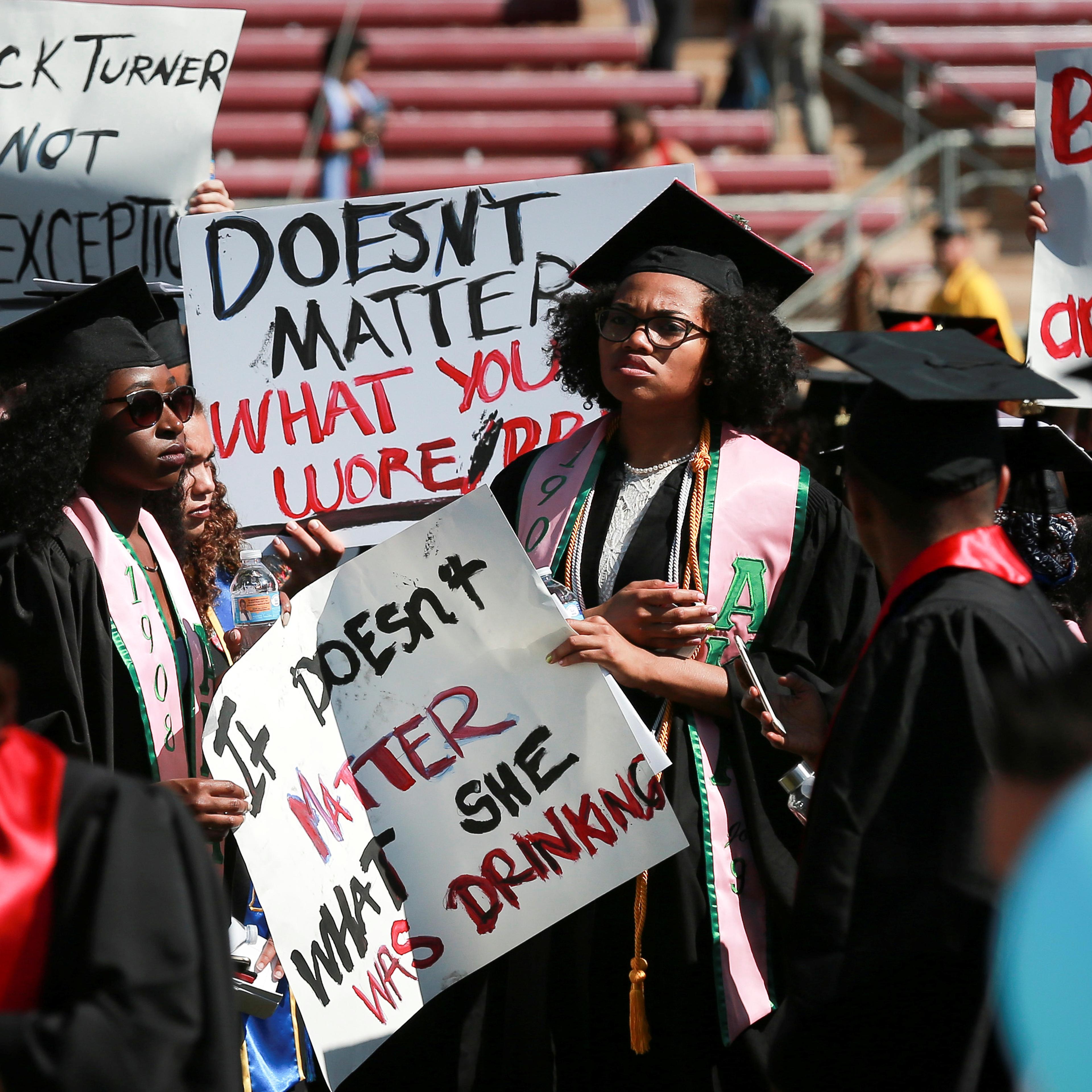 Protesters hold signs to raise awareness of sexual assault on campus in the wake of the national attention brought by the Stanford rape case at the Stanford University commencement ceremony in Palo Alto, California