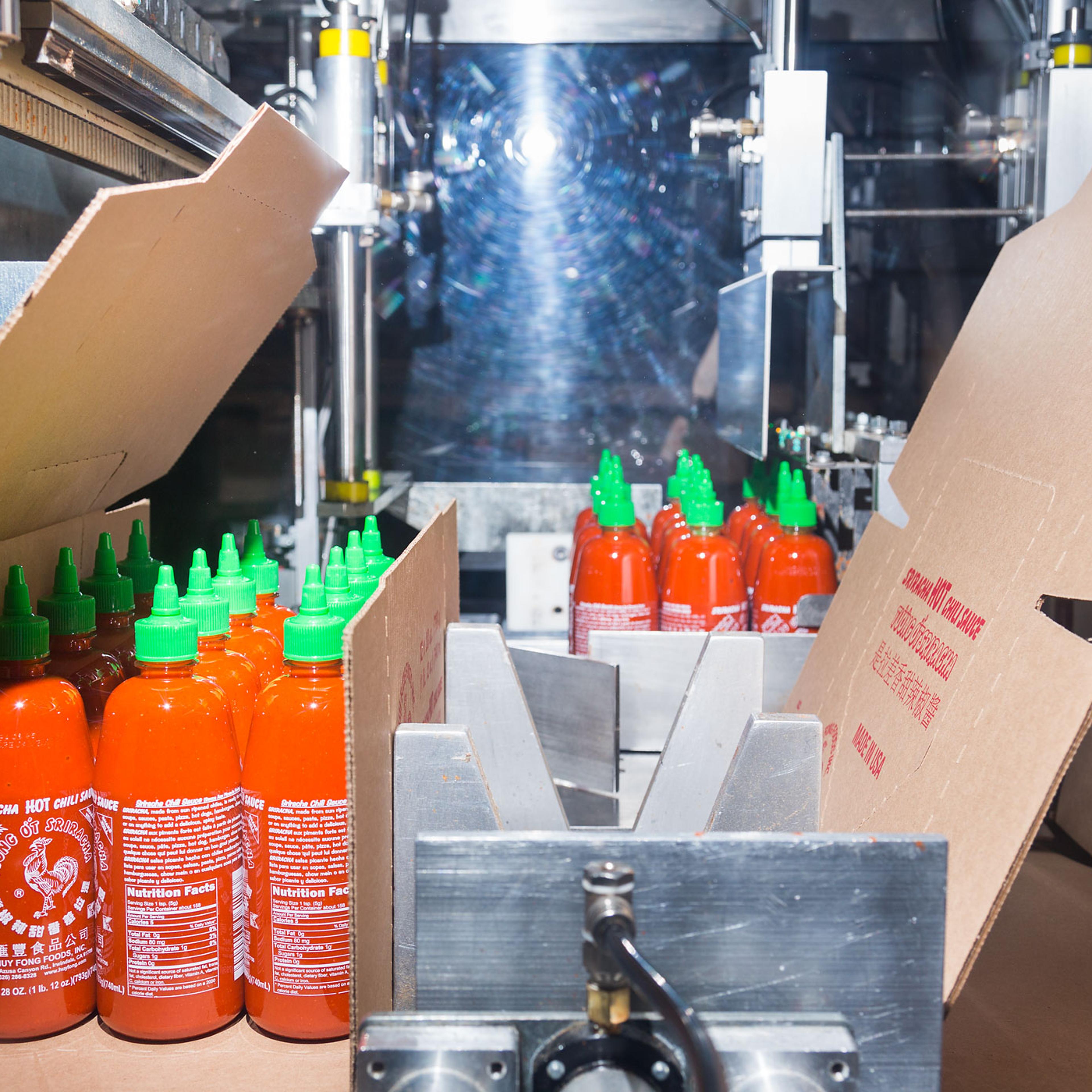 A machine boxes Sriracha for shipping.