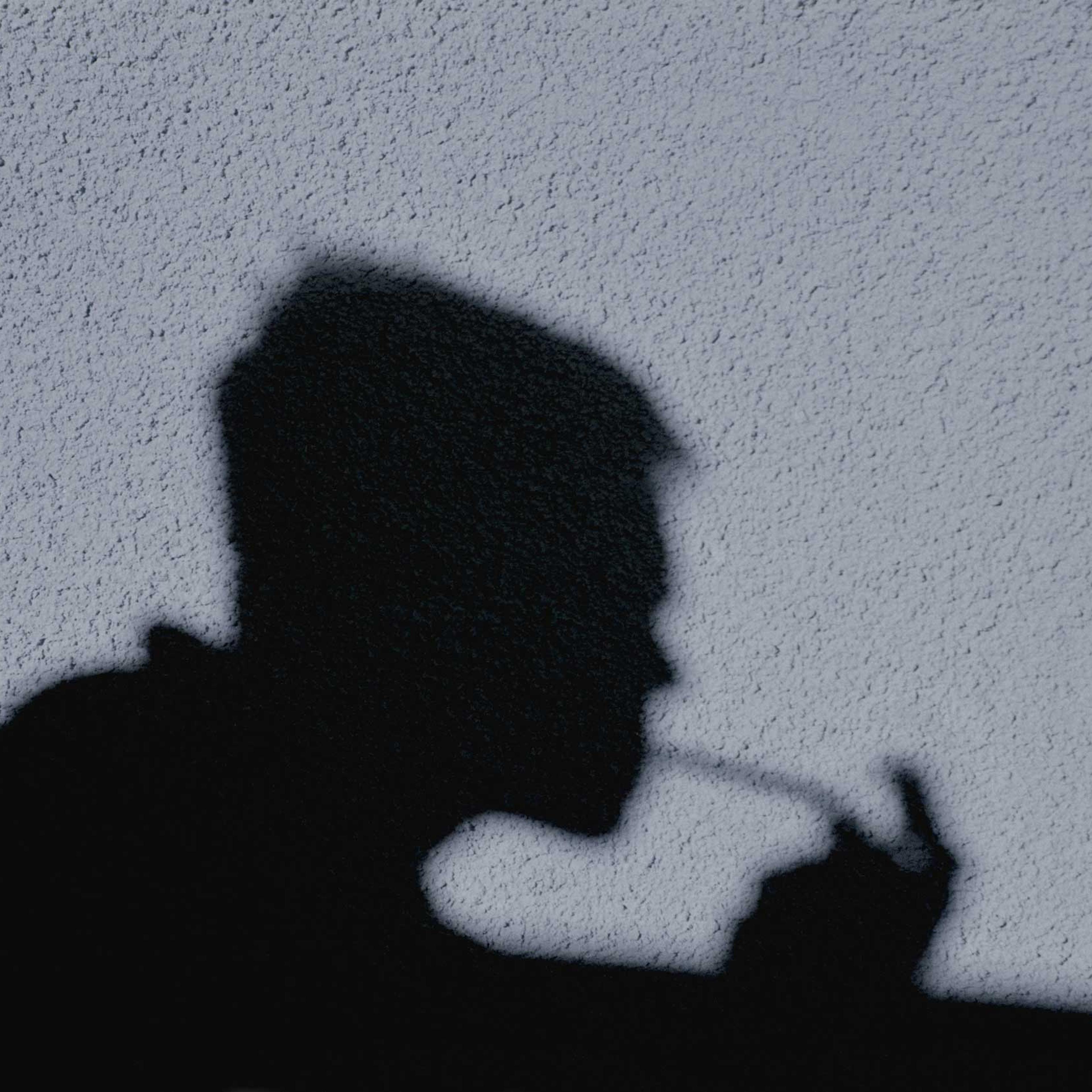 Shadow of man smoking crack cast on wall, side view