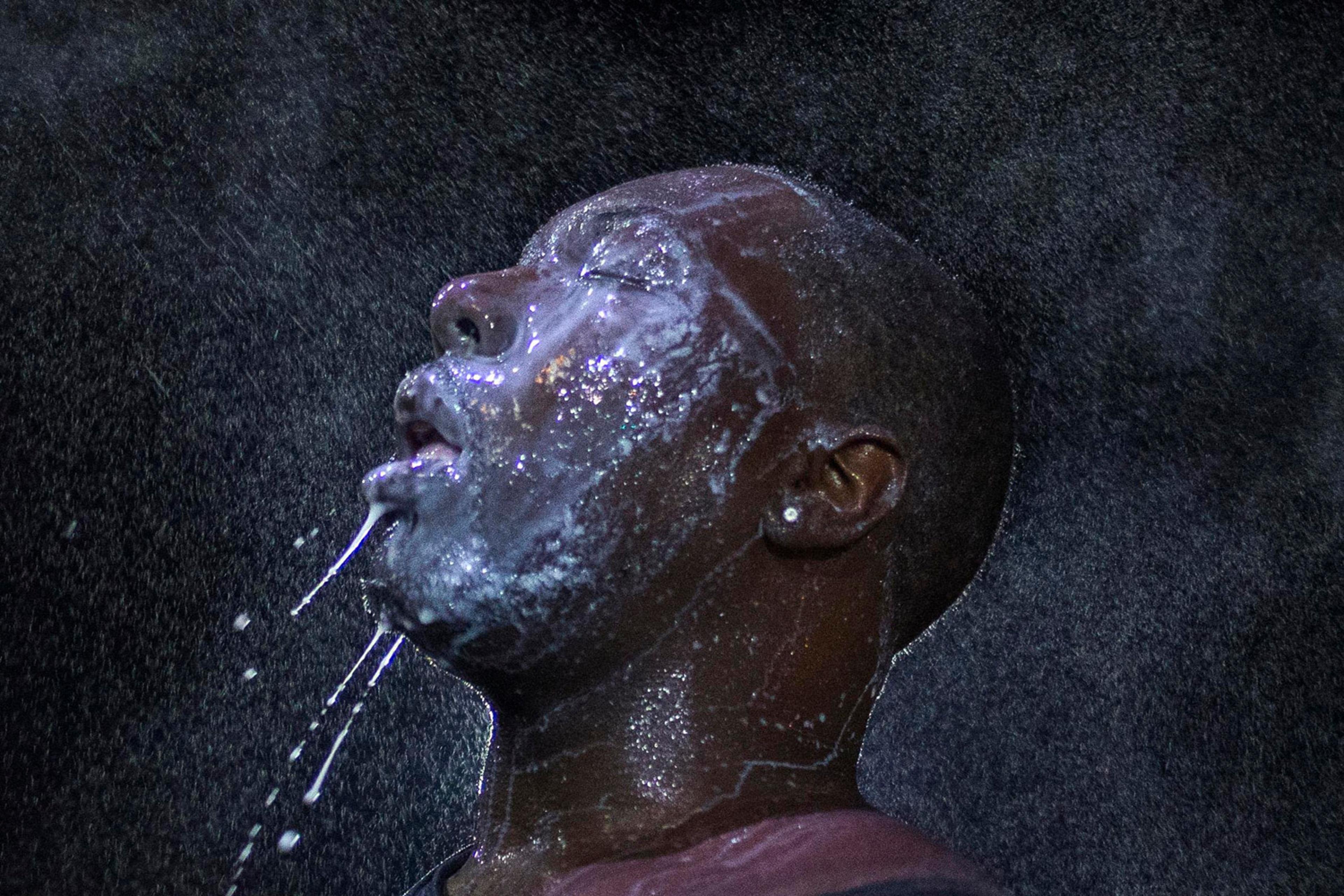 A man is doused with milk and sprayed with mist after being hit by an eye irritant from security forces trying to disperse demonstrators protesting against the shooting of Brown in Ferguson