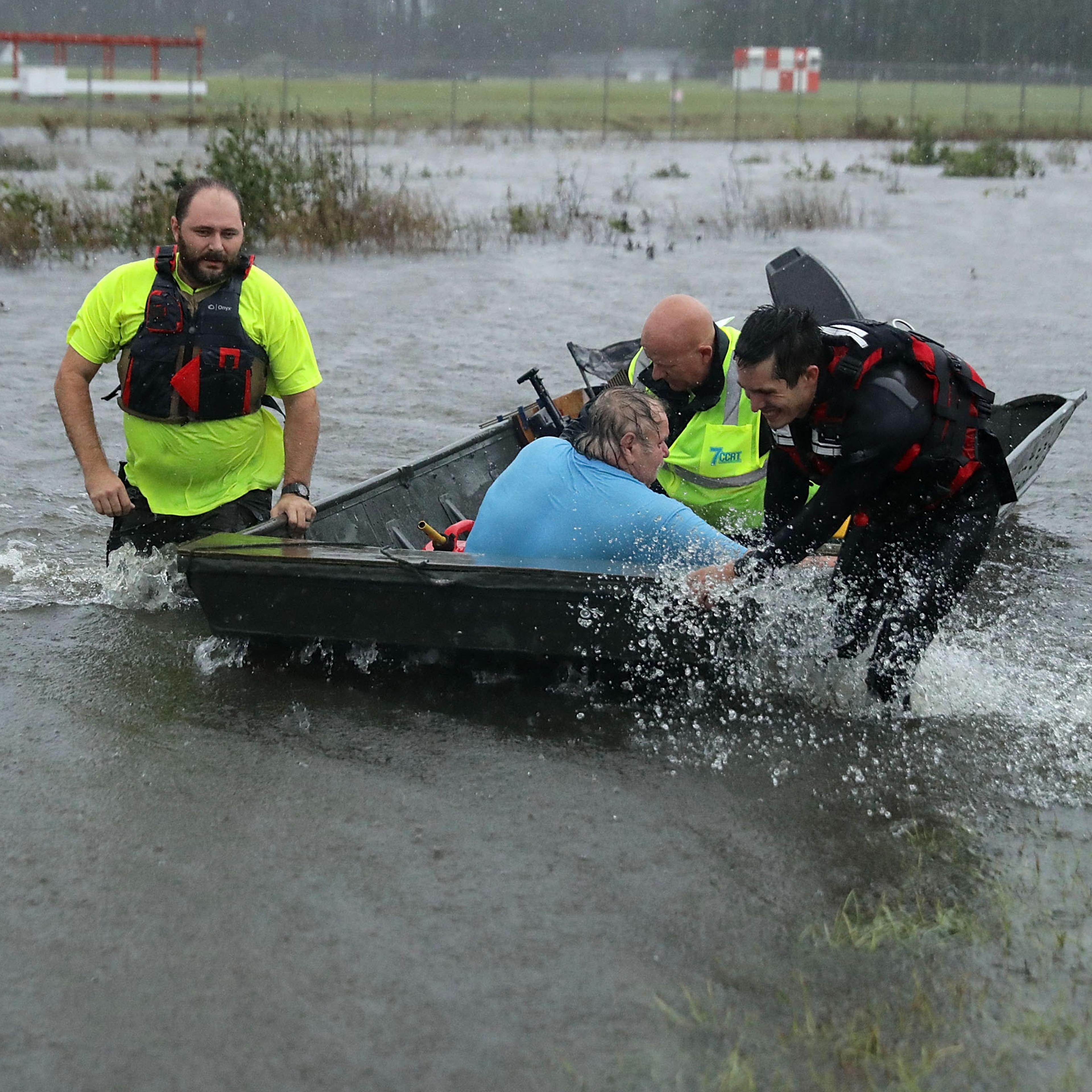 Volunteers rescuing a man and helping him into a boat