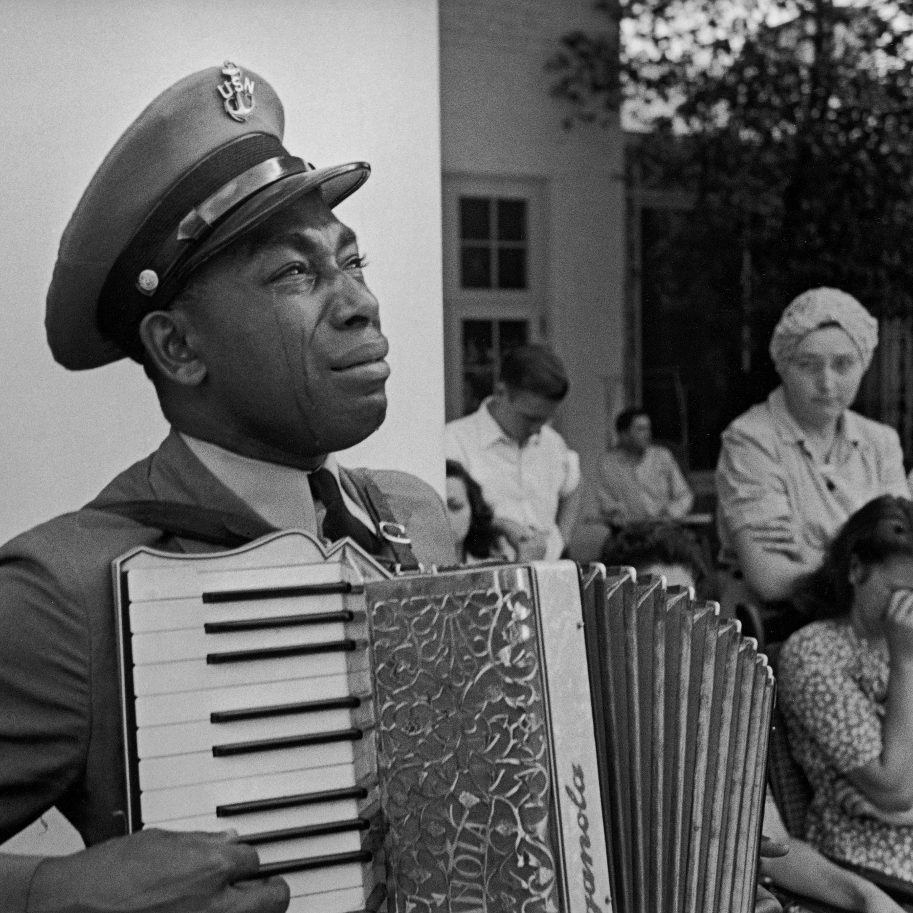 Tears stream down the cheeks of accordion-playing Chief Petty Officer (USN) Graham Jackson as President Franklin D. Roosevelt's flag-draped funeral train leaves Warm Springs, Ga., April 13, 1945.