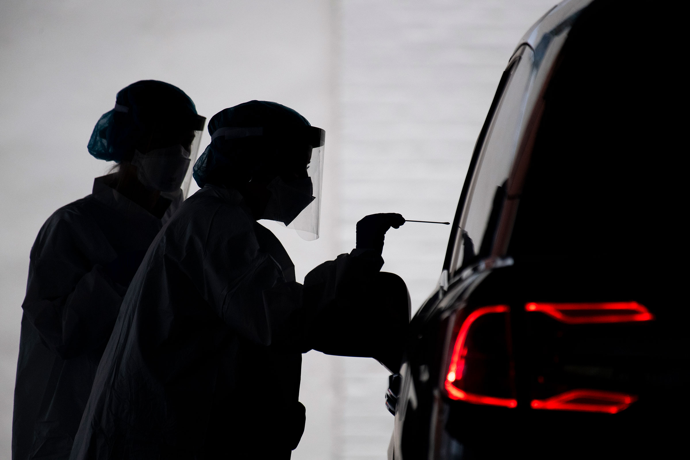 A healthcare worker conducts a COVID-19 test at a drive-thru testing facility at George Washington University on Tuesday, May 5, 2020.