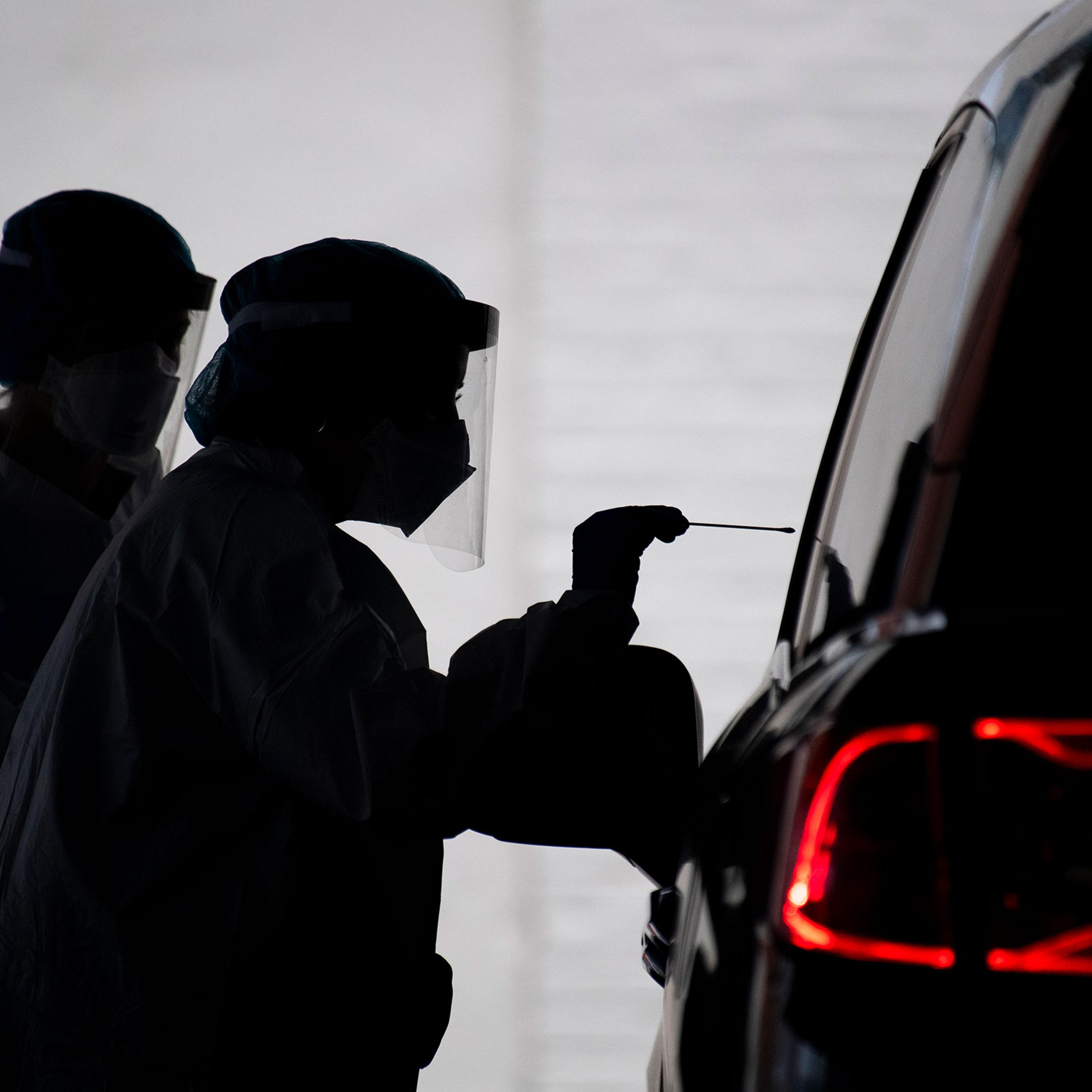 A healthcare worker conducts a COVID-19 test at a drive-thru testing facility at George Washington University on Tuesday, May 5, 2020.