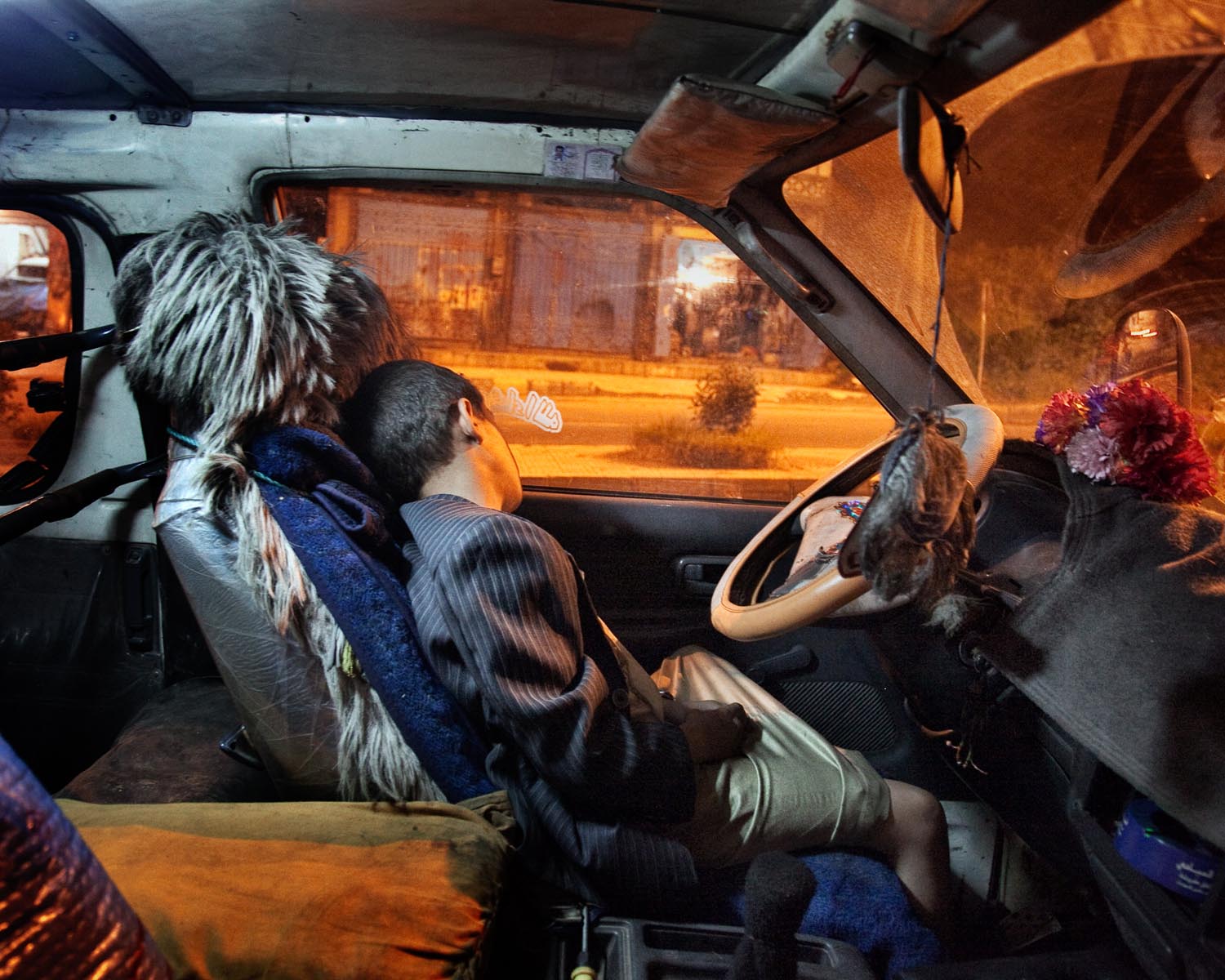 A boy sleeps inside a car in the southwestern city of Ibb, Yemen. August 2010.