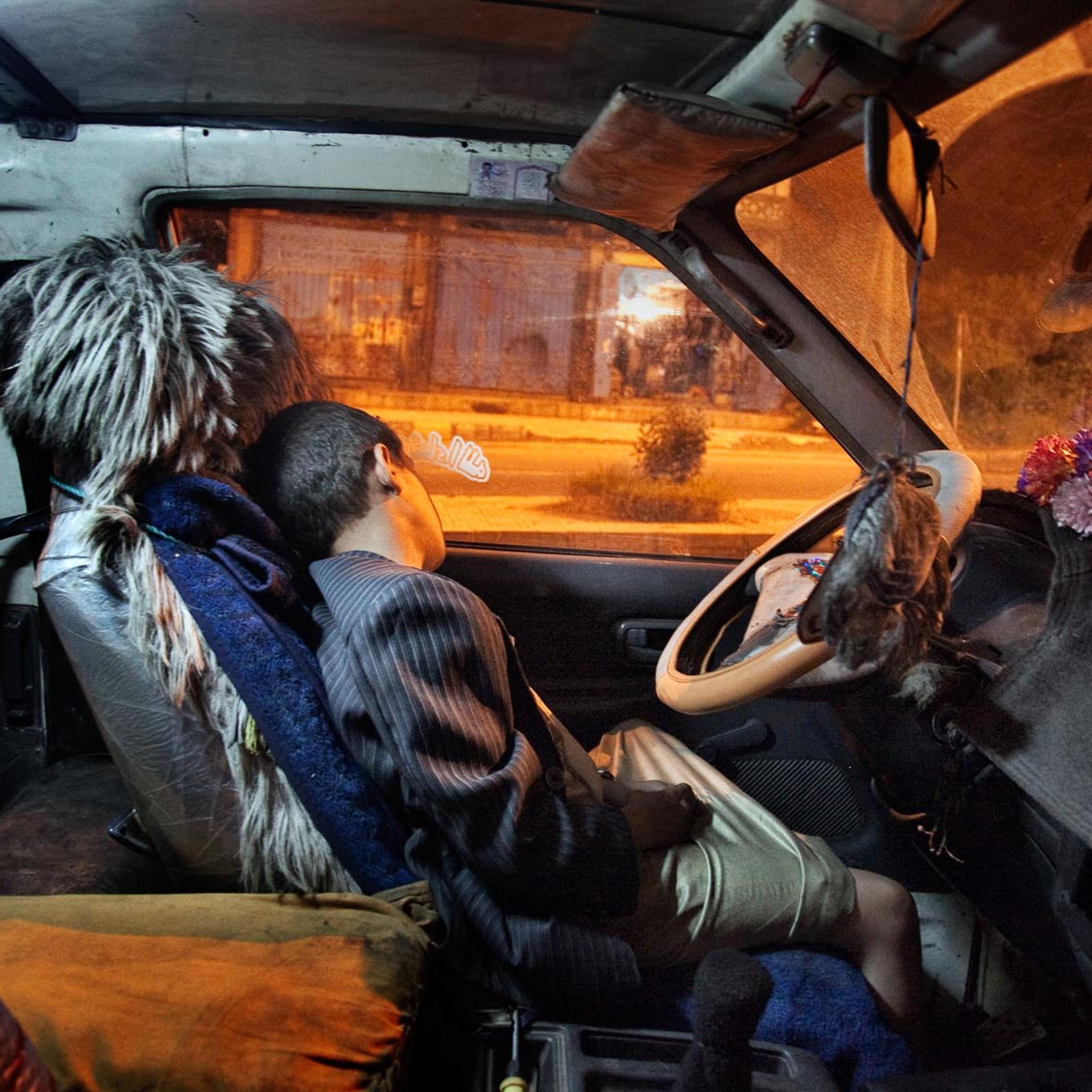A boy sleeps inside a car in the southwestern city of Ibb, Yemen. August 2010.