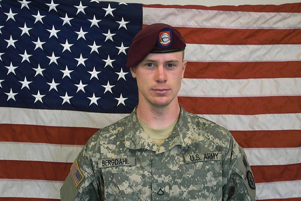 In this undated image provided by the U.S. Army, Sgt. Bowe Bergdahl poses in front of an American flag.