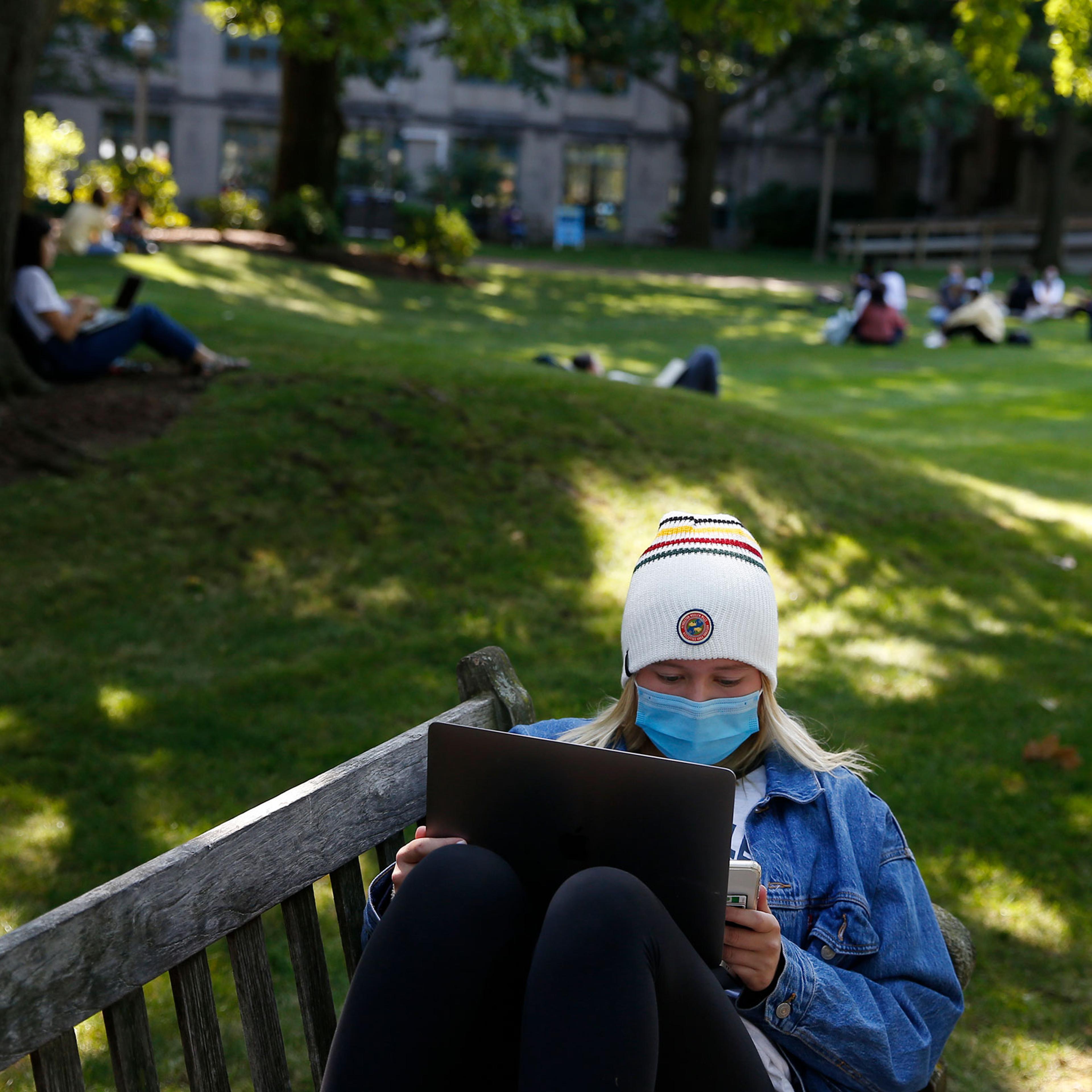 A student wears a mask to protect against the spread of COVID-19 as she worked on her laptop outside at Boston University, on Sept. 23, 2020.