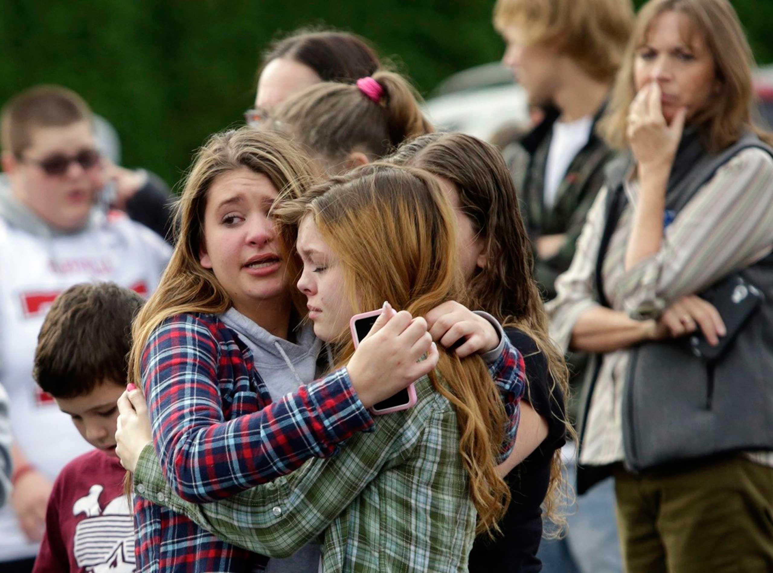 Two girls hug at Shoultes Gospel Hall church where families are reuniting after an active shooter situation at Marysville-Pilchuck High School in Marysville, Washington