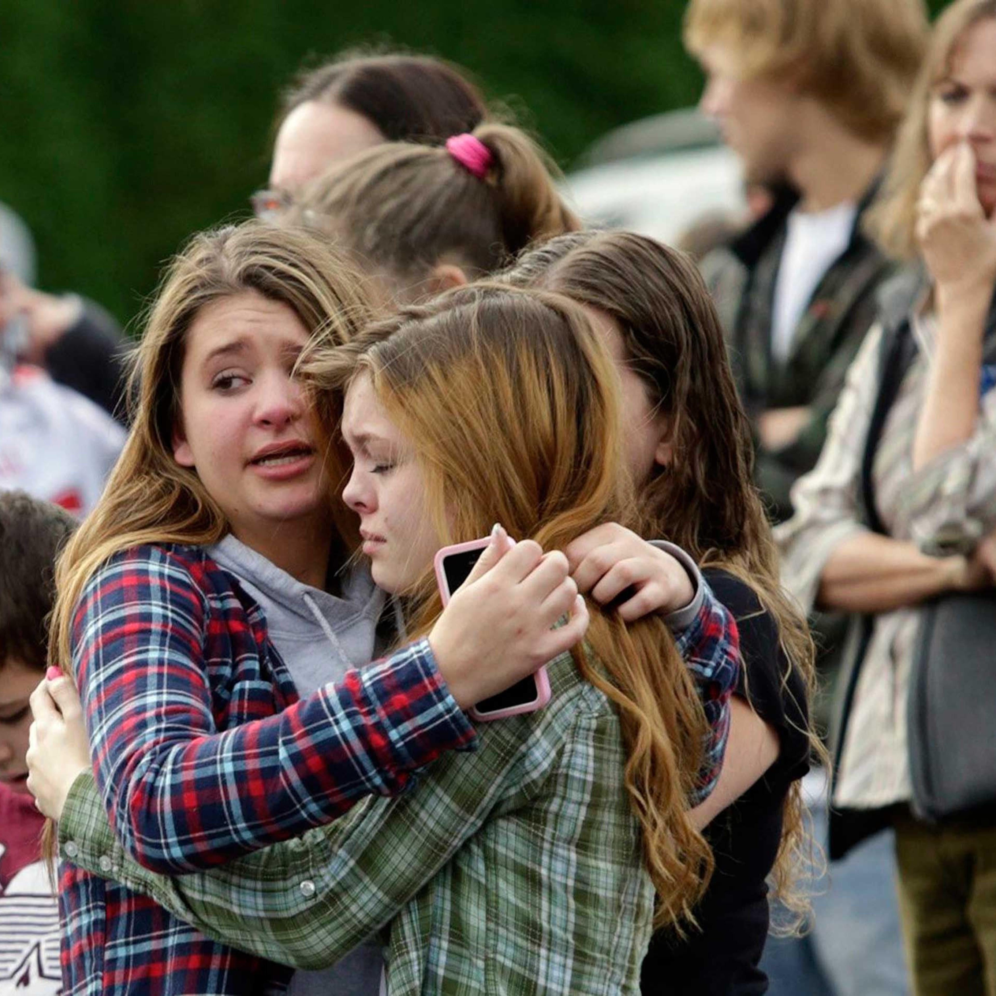 Two girls hug at Shoultes Gospel Hall church where families are reuniting after an active shooter situation at Marysville-Pilchuck High School in Marysville, Washington