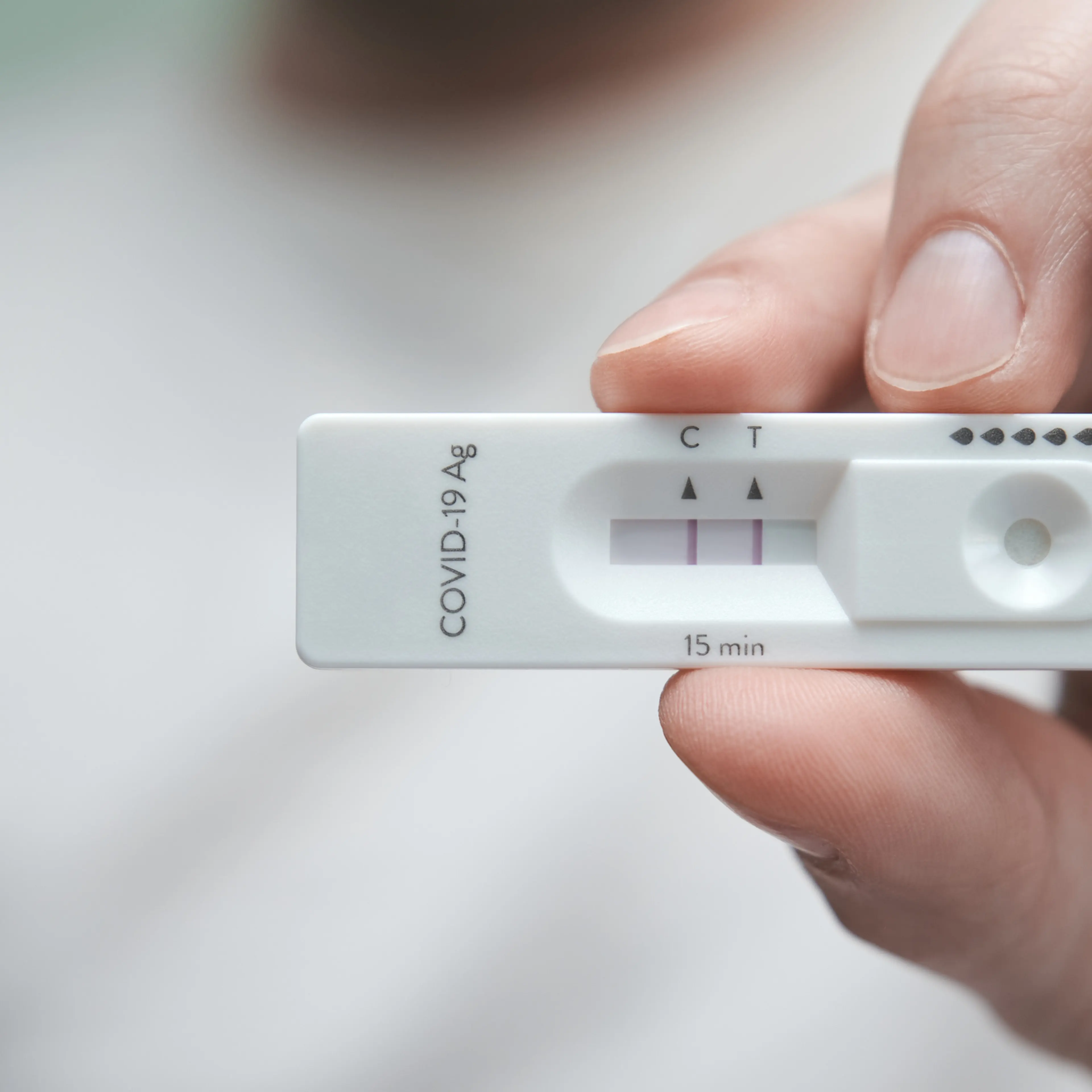 Close-up of a hand holding a positive antigen test for COVID-19.