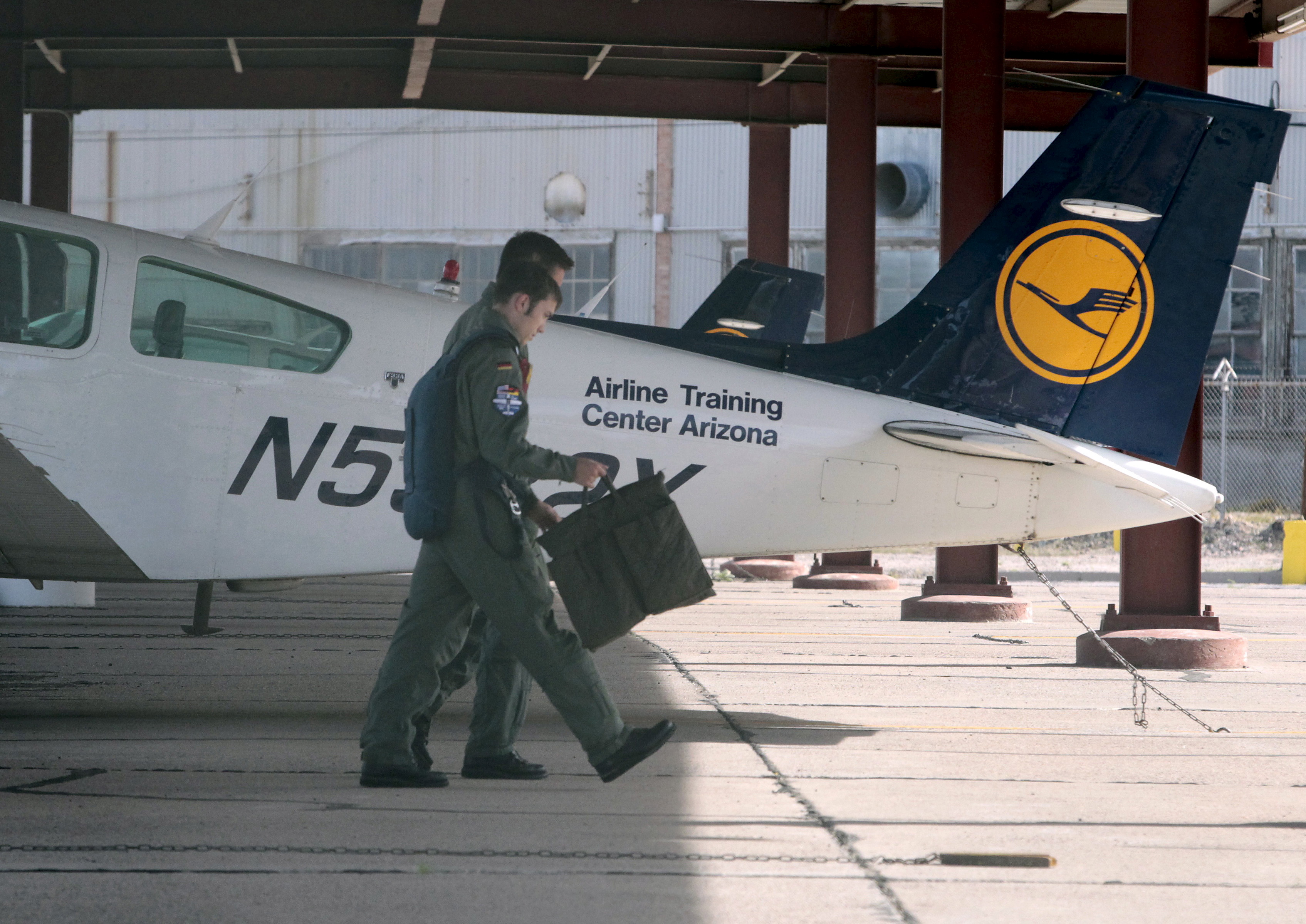 Pilots walk past a light aircraft trainer at the Airline Training Center Arizona in Goodyear, Arizona