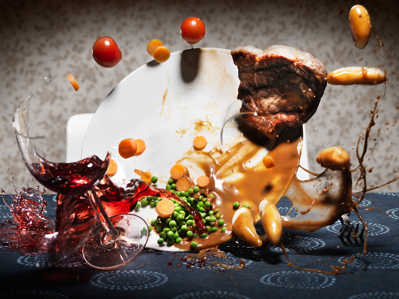 Broken wineglass and food plate falling on table