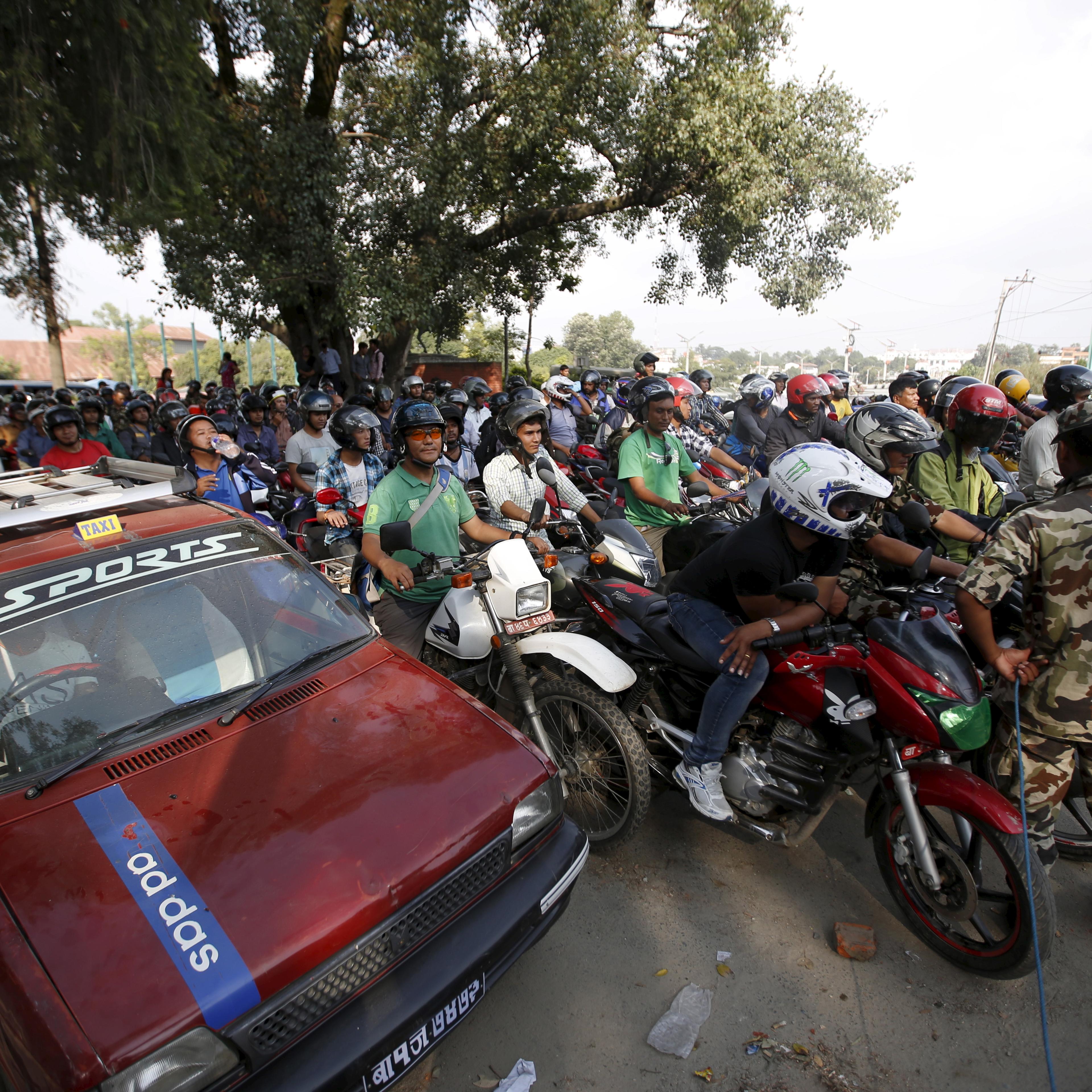 Nepalese people wait in a queue to fill petrol for their vehicle near a petrol station in Kathmandu