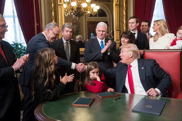 President Donald Trump shakes hands with Senate Minority Leader Chuck Schumer, D-N.Y, as he is joined by the Congressional leadership and his family while he formally signs his cabinet nominations into law, in the President's Room of the Senate, at the C