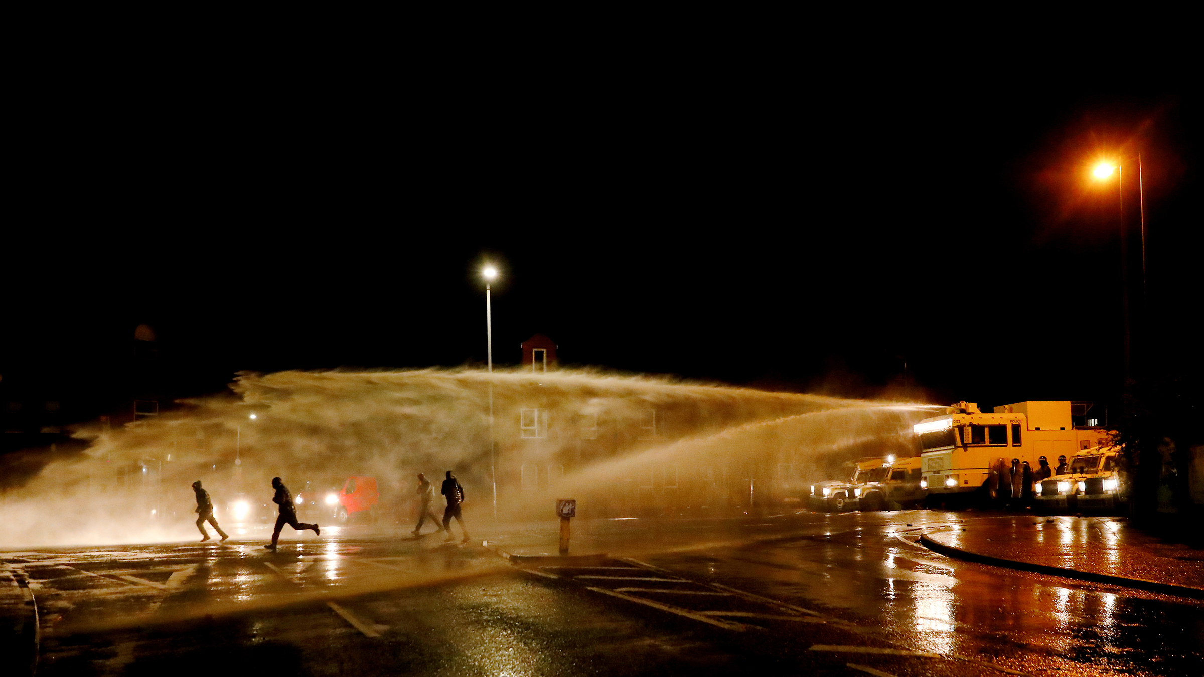 Rioters react as the police uses a water cannon on Springfield Road as protests continue in Belfast on April 8