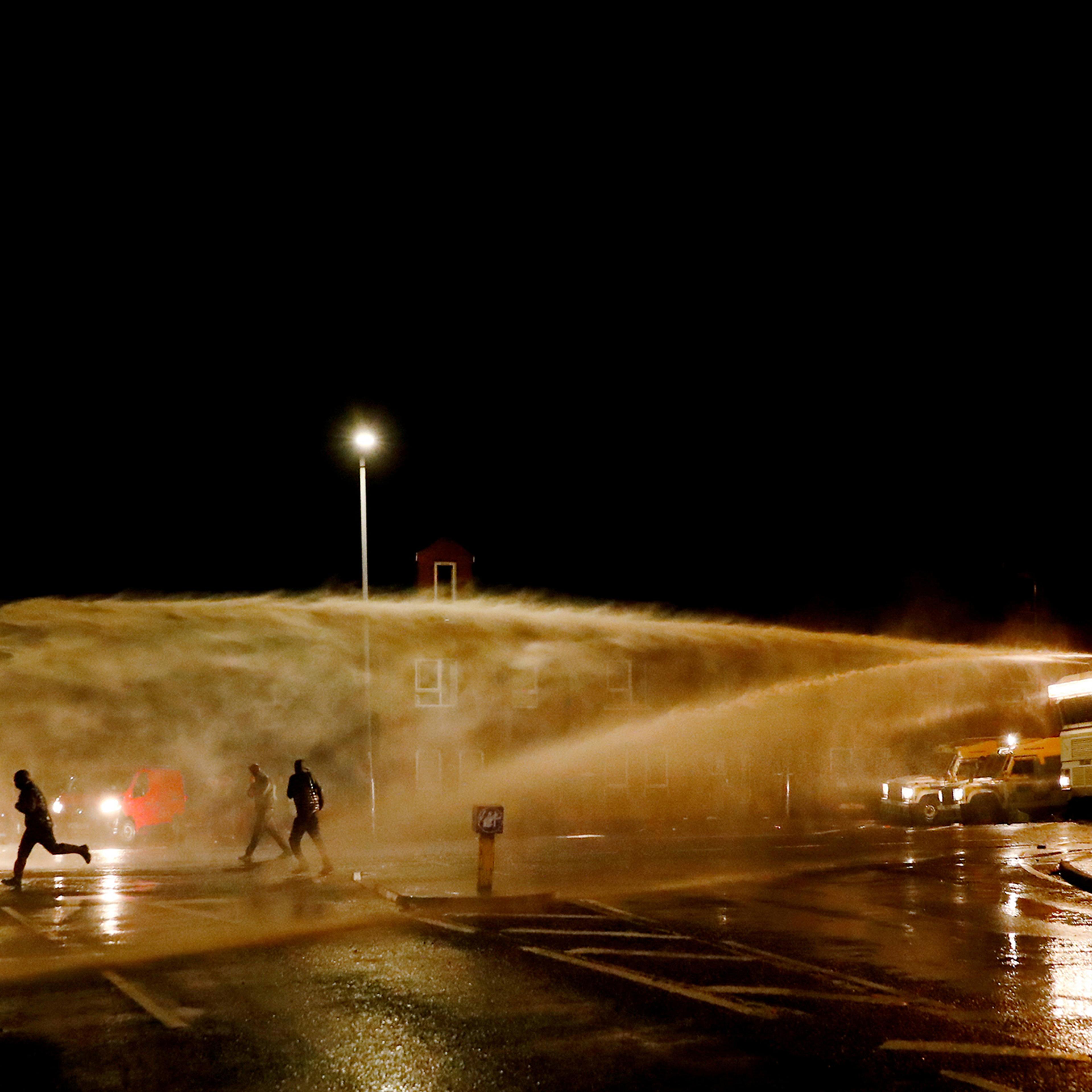 Rioters react as the police uses a water cannon on Springfield Road as protests continue in Belfast on April 8