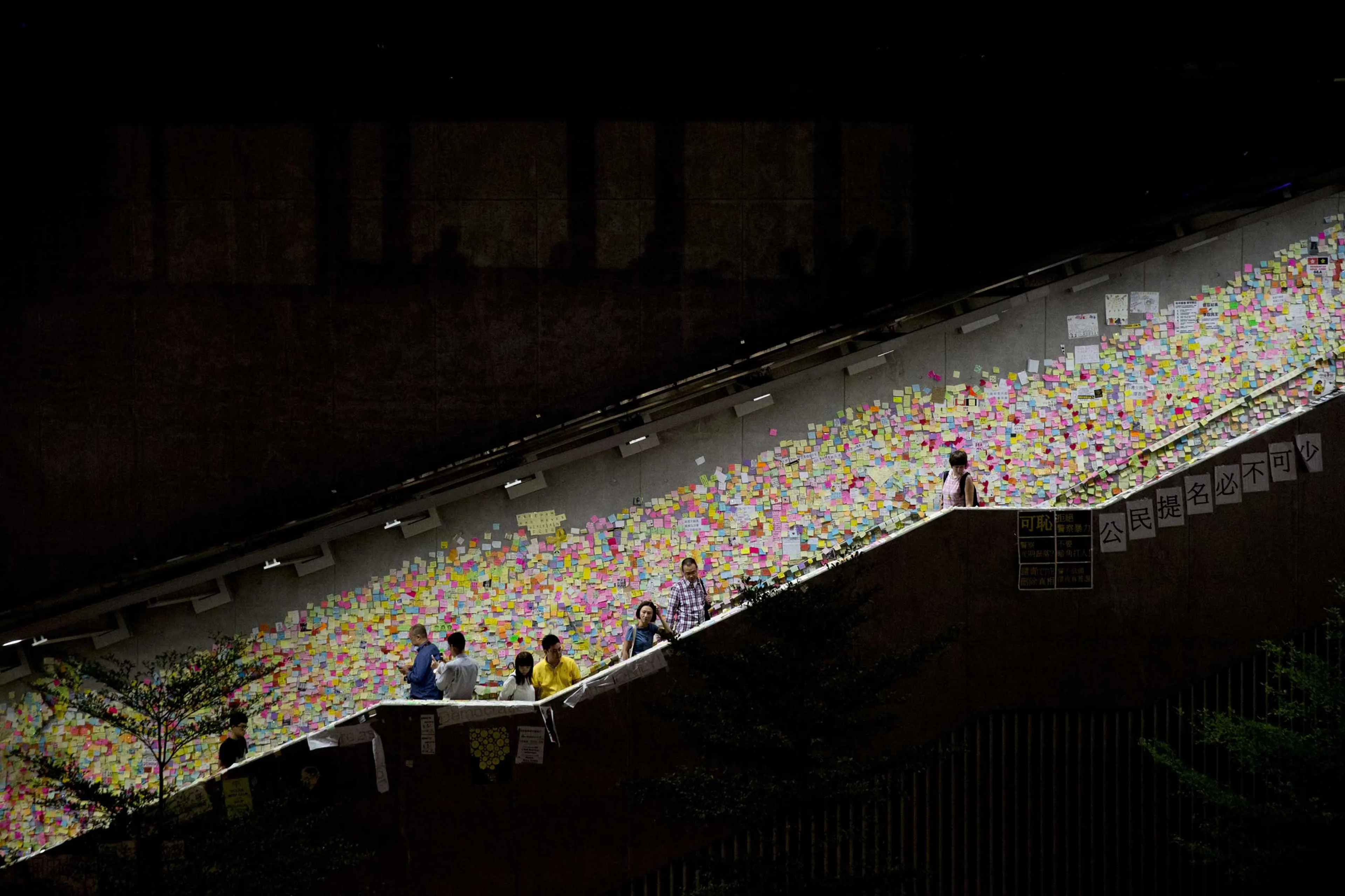 Demonstrators walk past notes hanging on a wall outside the Central Government Offices in the Admiralty business district in Hong Kong on Oct. 17, 2014.