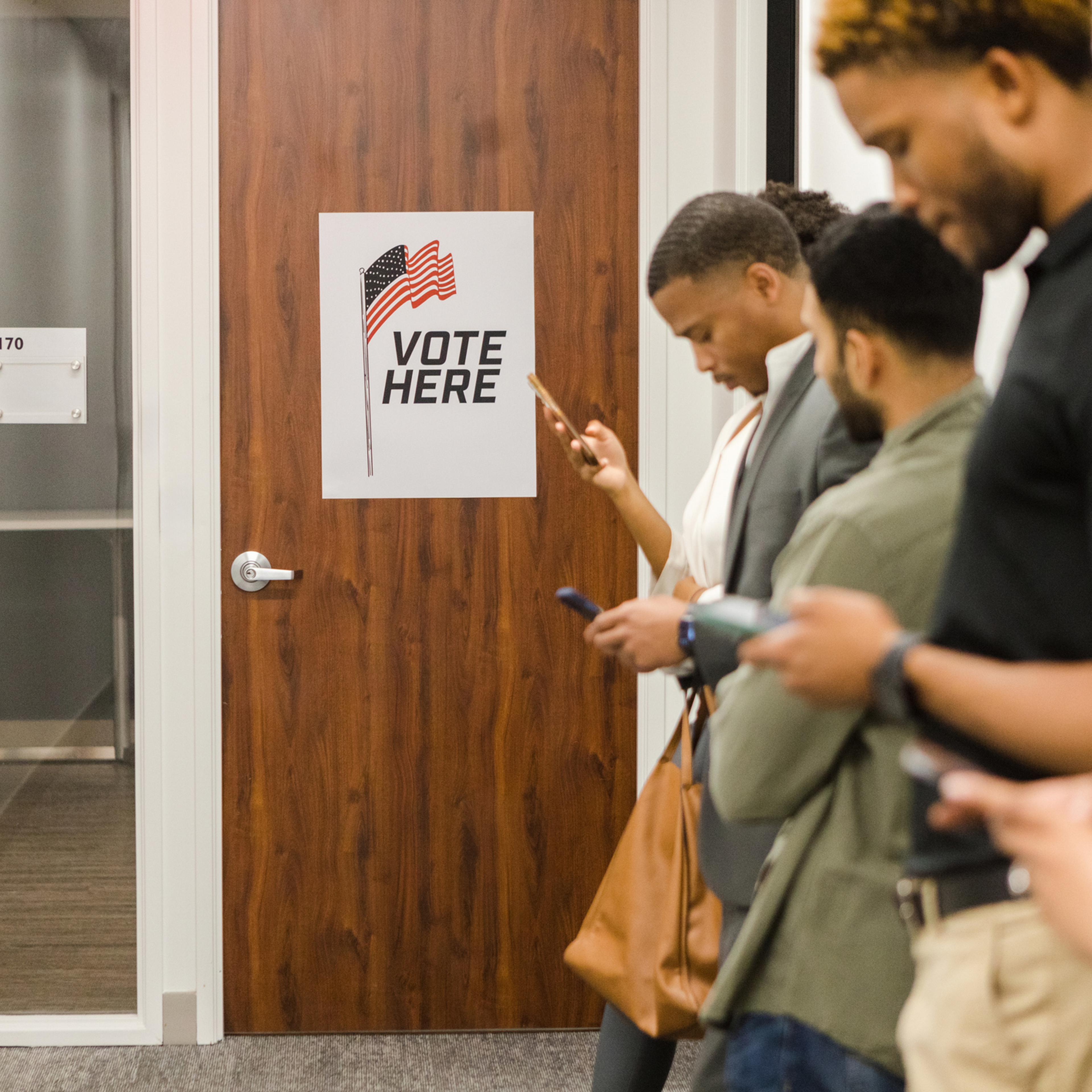 Group of people stand in line at the community center waiting to vote