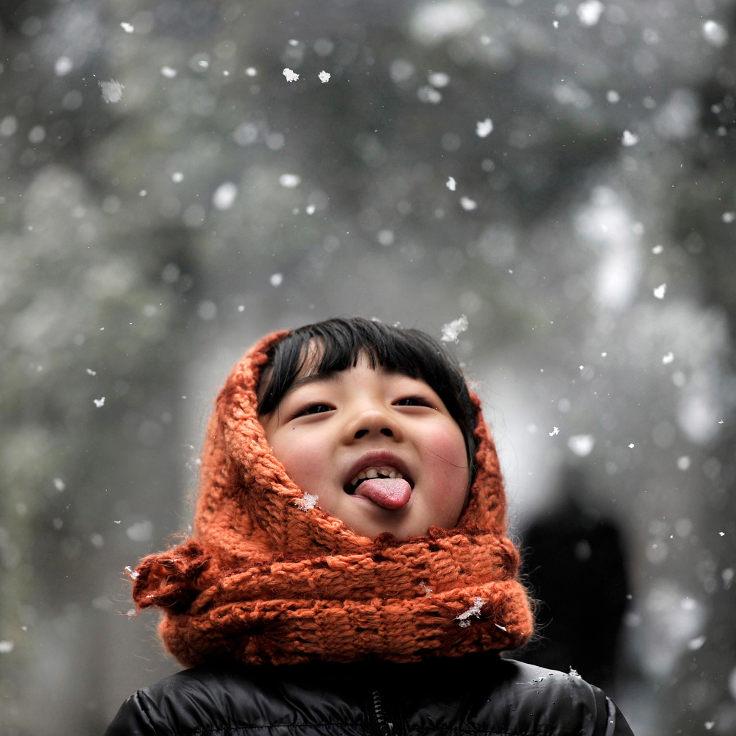 A girl sticks out her tongue during snowfalls on a street in Hefei