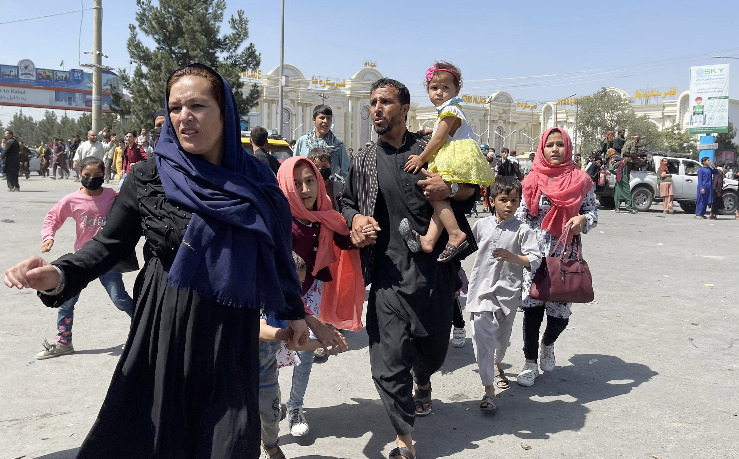 An Afghan family rushes to the Hamid Karzai International Airport as they flee Kabul, Afghanistan, on August 16, 2021.
