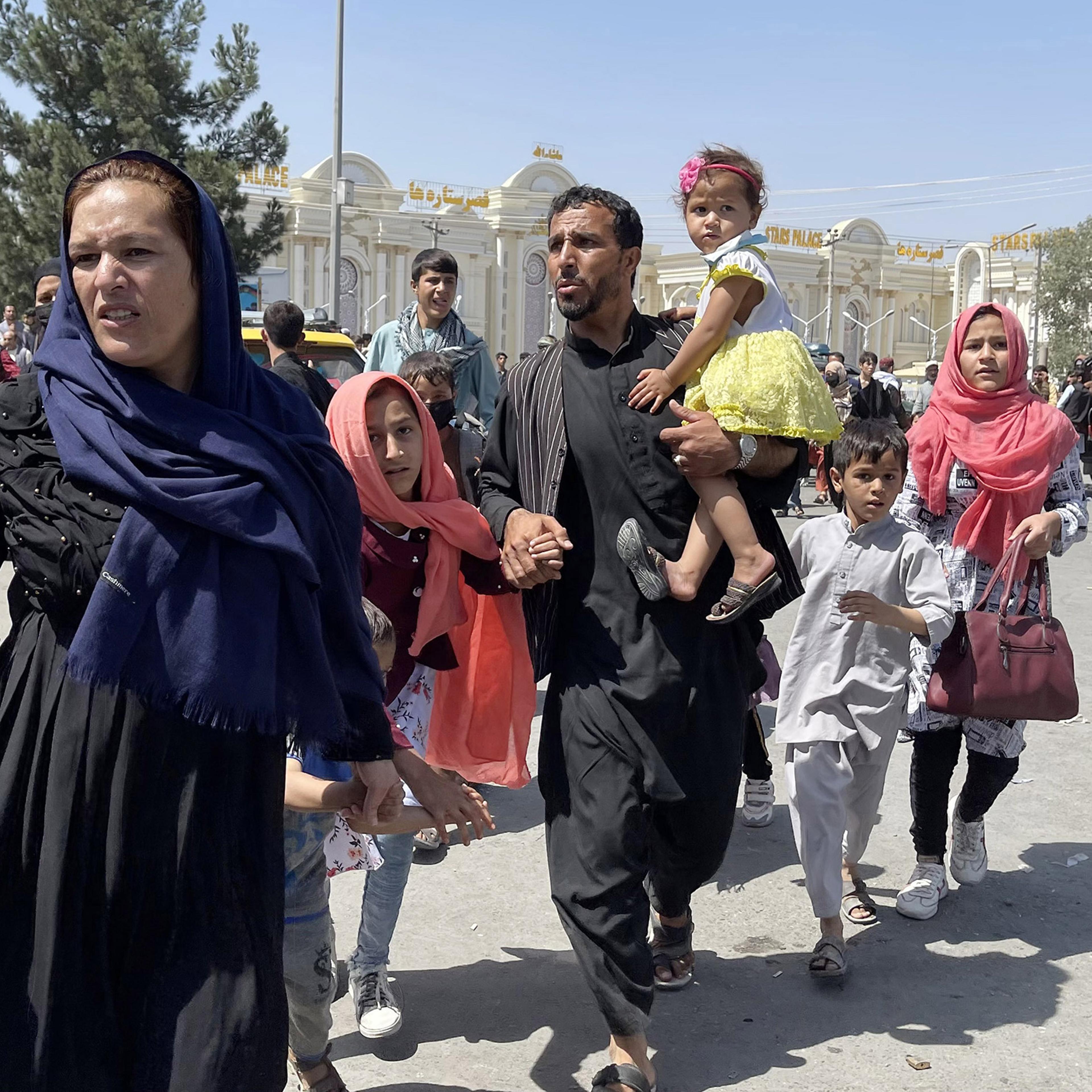 An Afghan family rushes to the Hamid Karzai International Airport as they flee Kabul, Afghanistan, on August 16, 2021.