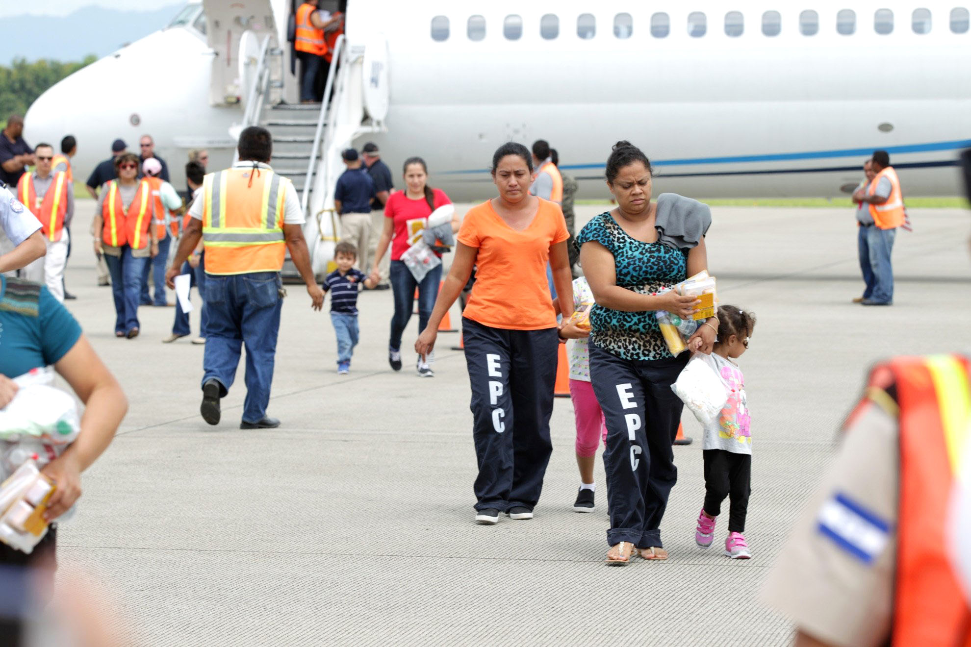 Women and their children walk on the tarmac after being deported from the U.S., at the Ramon Villeda international airport in San Pedro Sula on July 14, 2014.