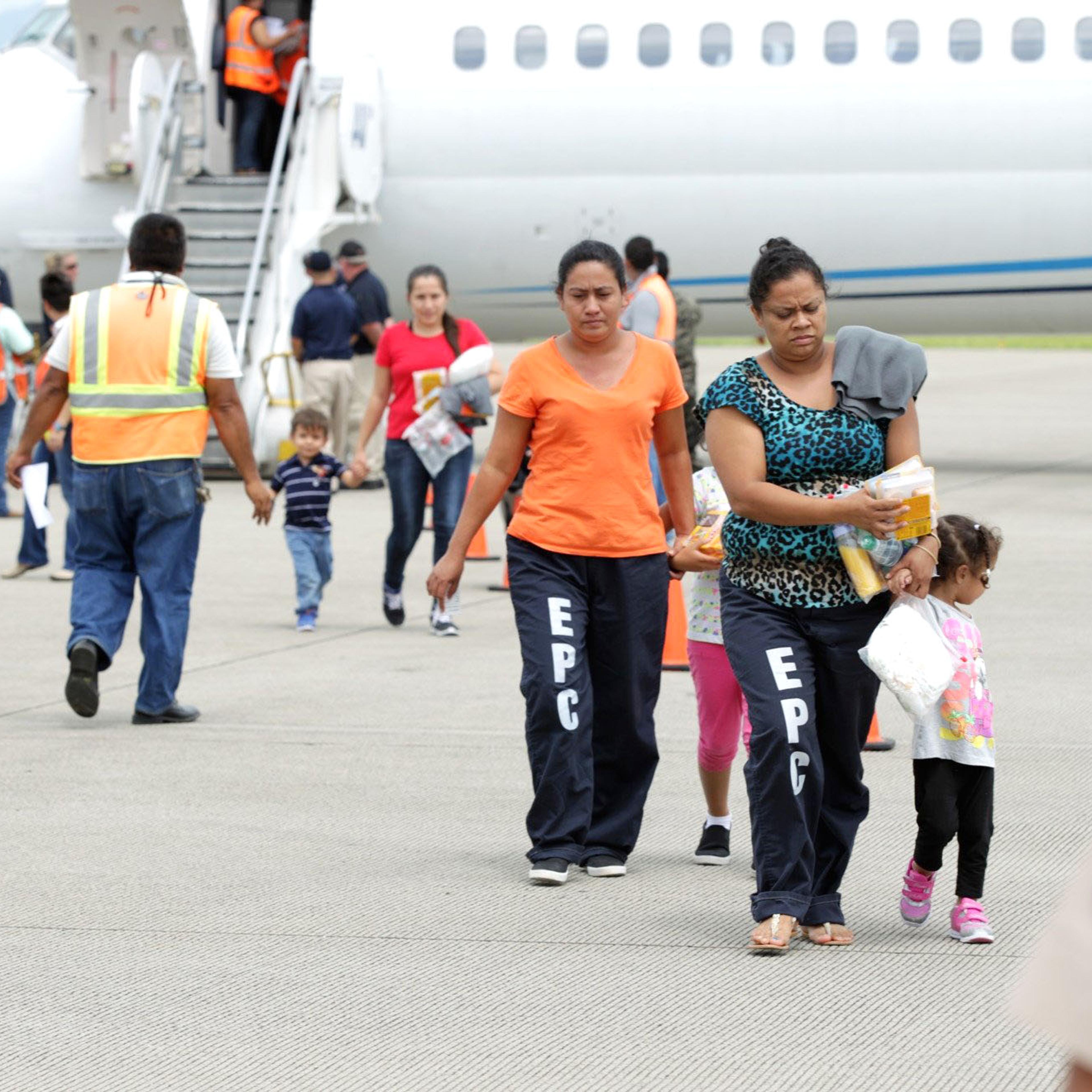 Women and their children walk on the tarmac after being deported from the U.S., at the Ramon Villeda international airport in San Pedro Sula on July 14, 2014.