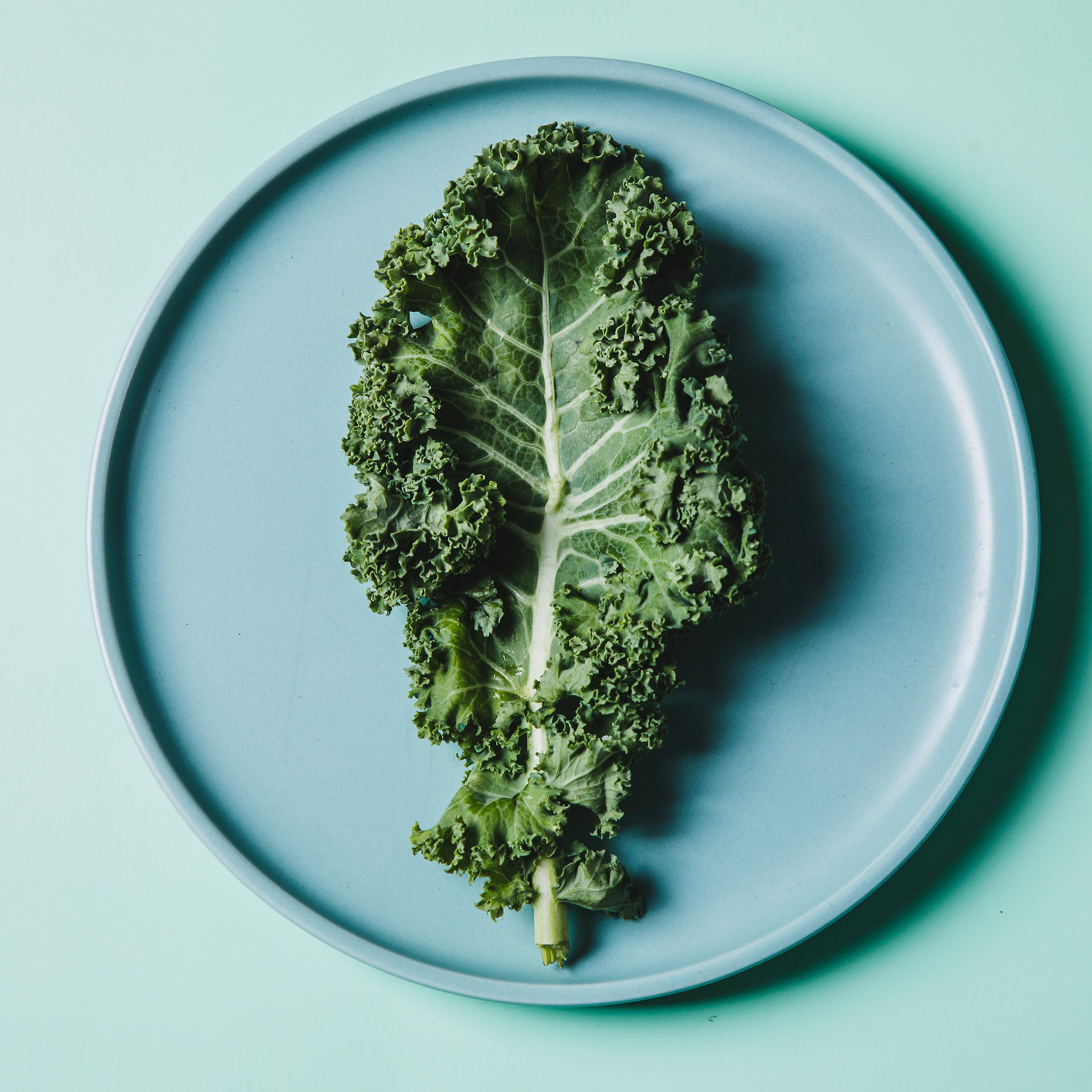 overhead view of kale on a plate against green background