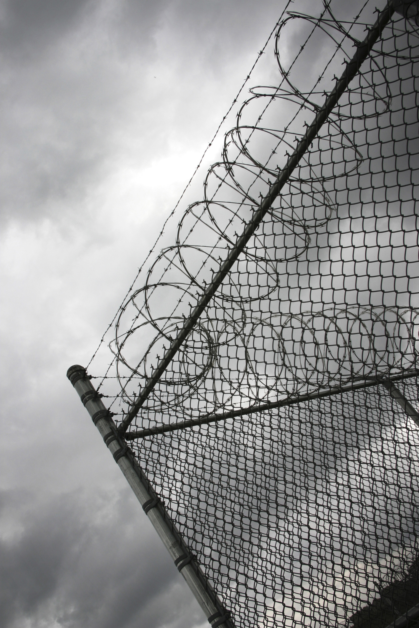 Jail Fence With Barbed Wire on Cloudy Day