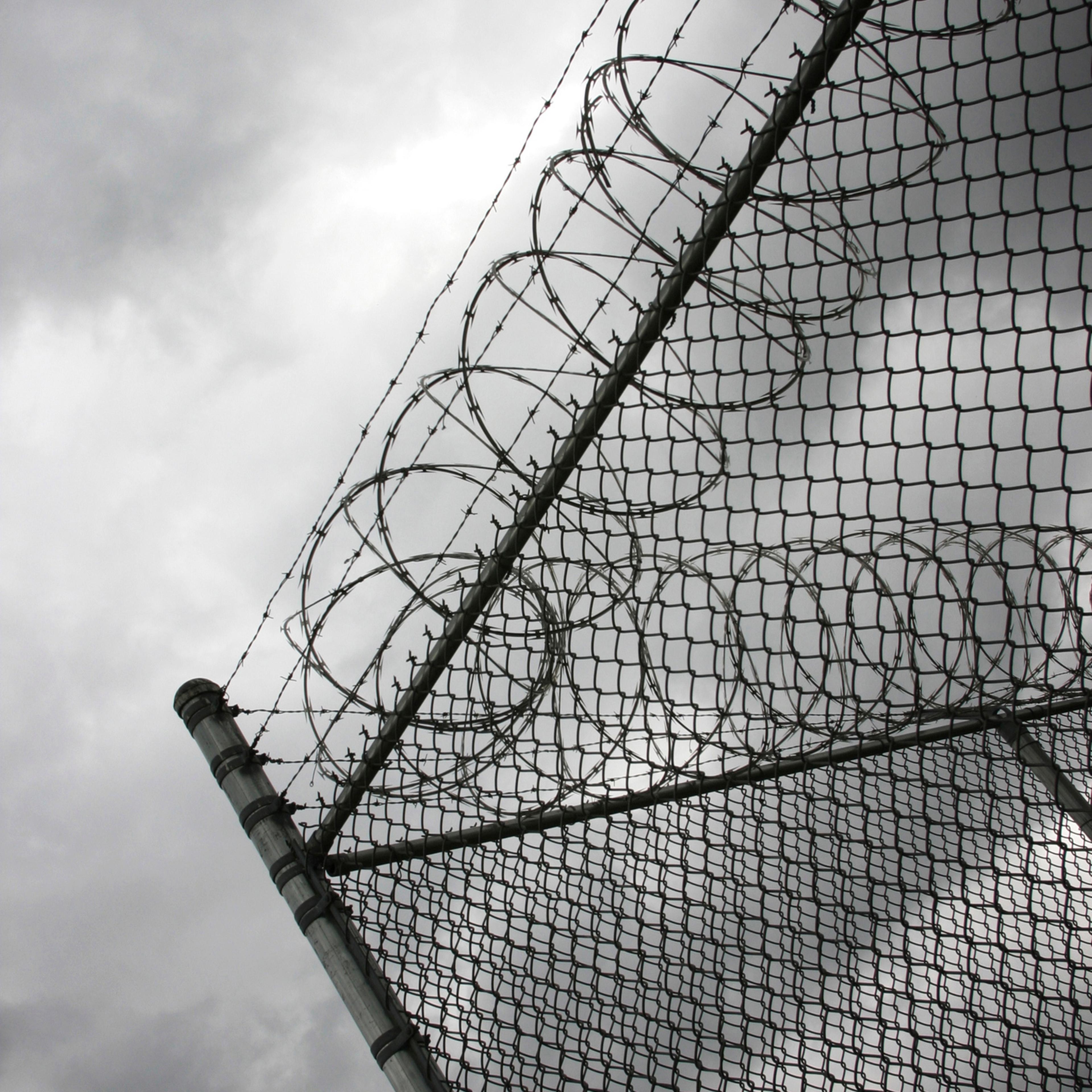 Jail Fence With Barbed Wire on Cloudy Day