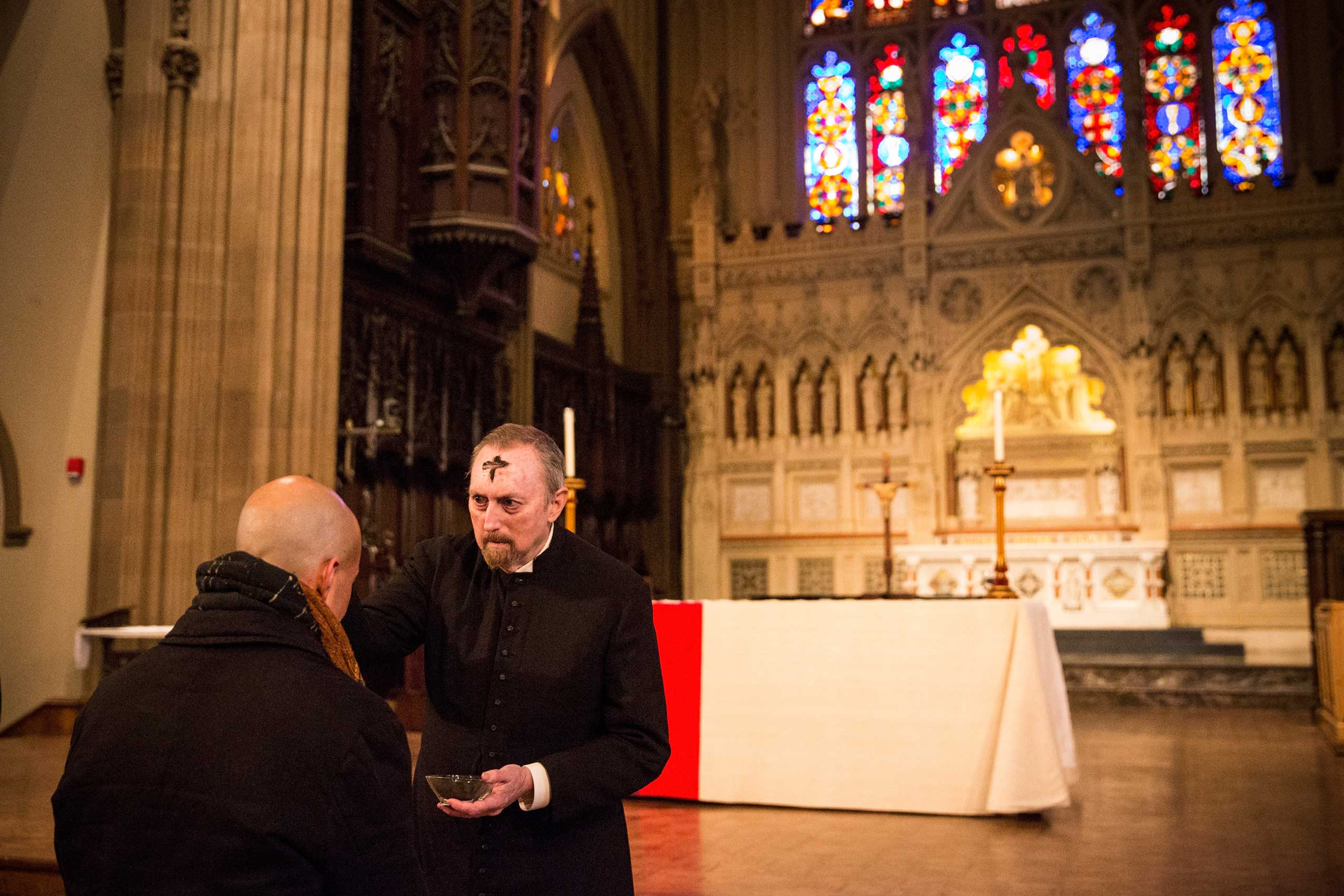John McCann, a layman at Trinity Church, draws a cross using ash on a man's forehead to symbolize Ash Wednesday, in New York in 2014.