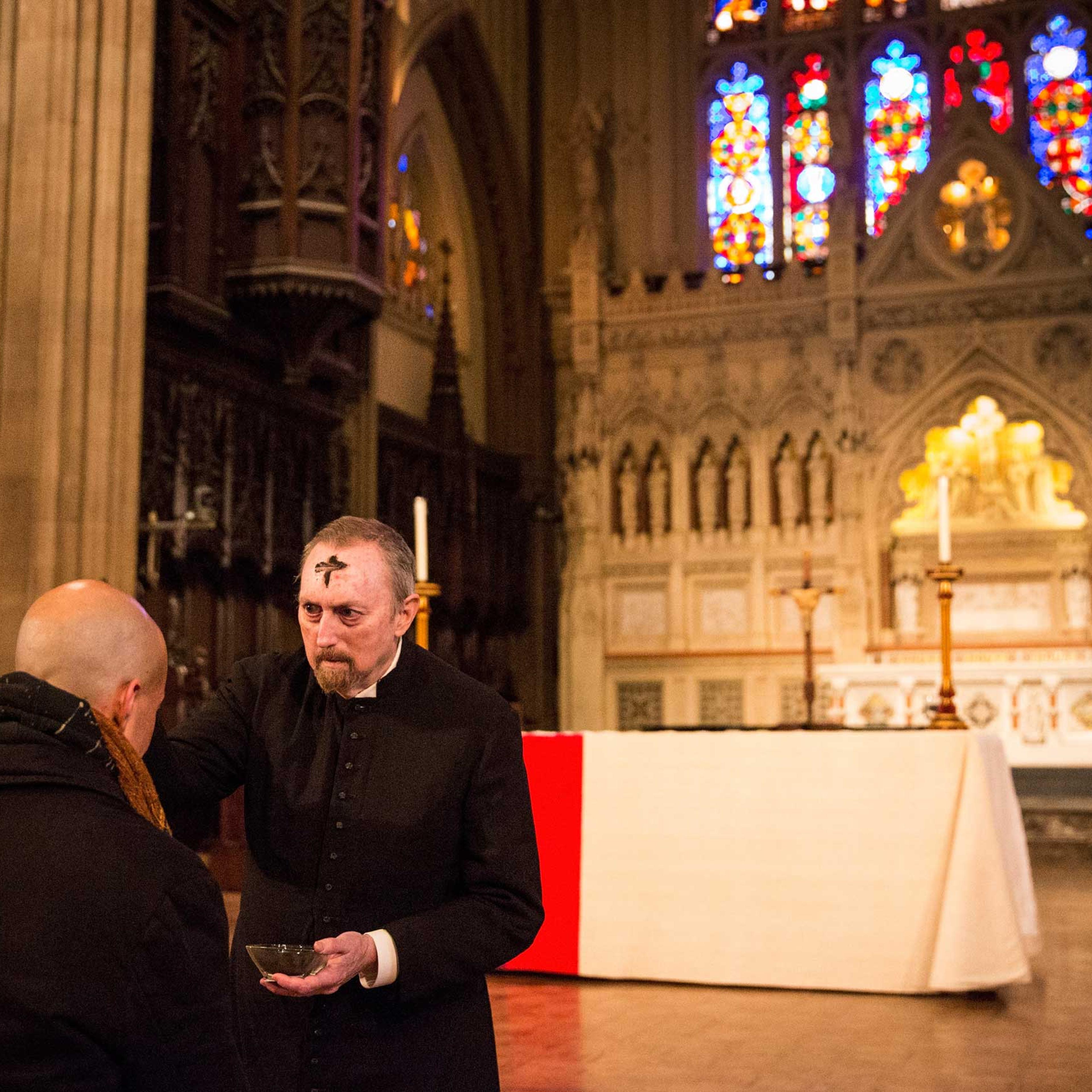John McCann, a layman at Trinity Church, draws a cross using ash on a man's forehead to symbolize Ash Wednesday, in New York in 2014.