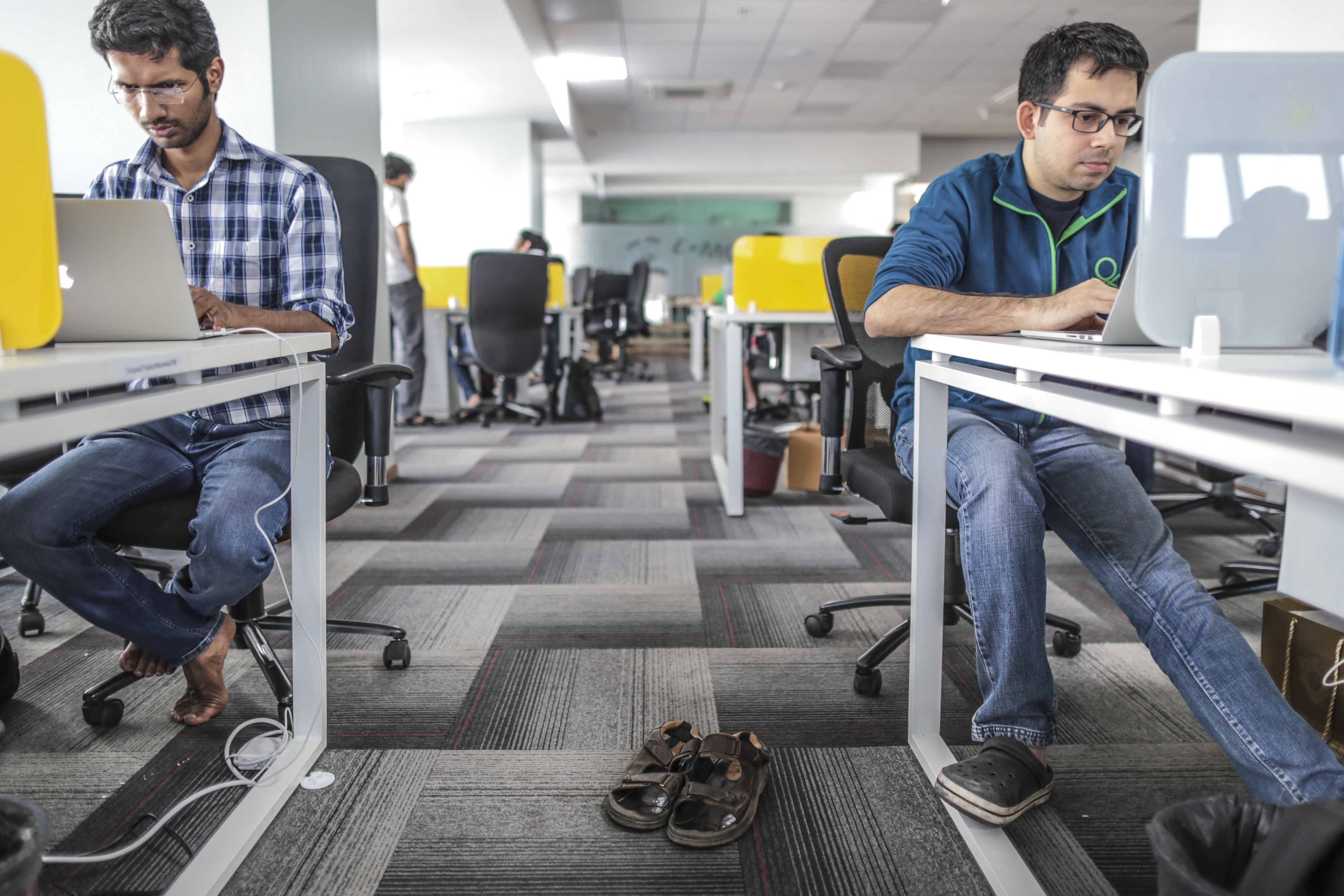 Tiny Owl employees work on laptop computers as pair of sandals sit on the floor inside the company's head office in Mumbai, India, on Monday, March. 9, 2015.