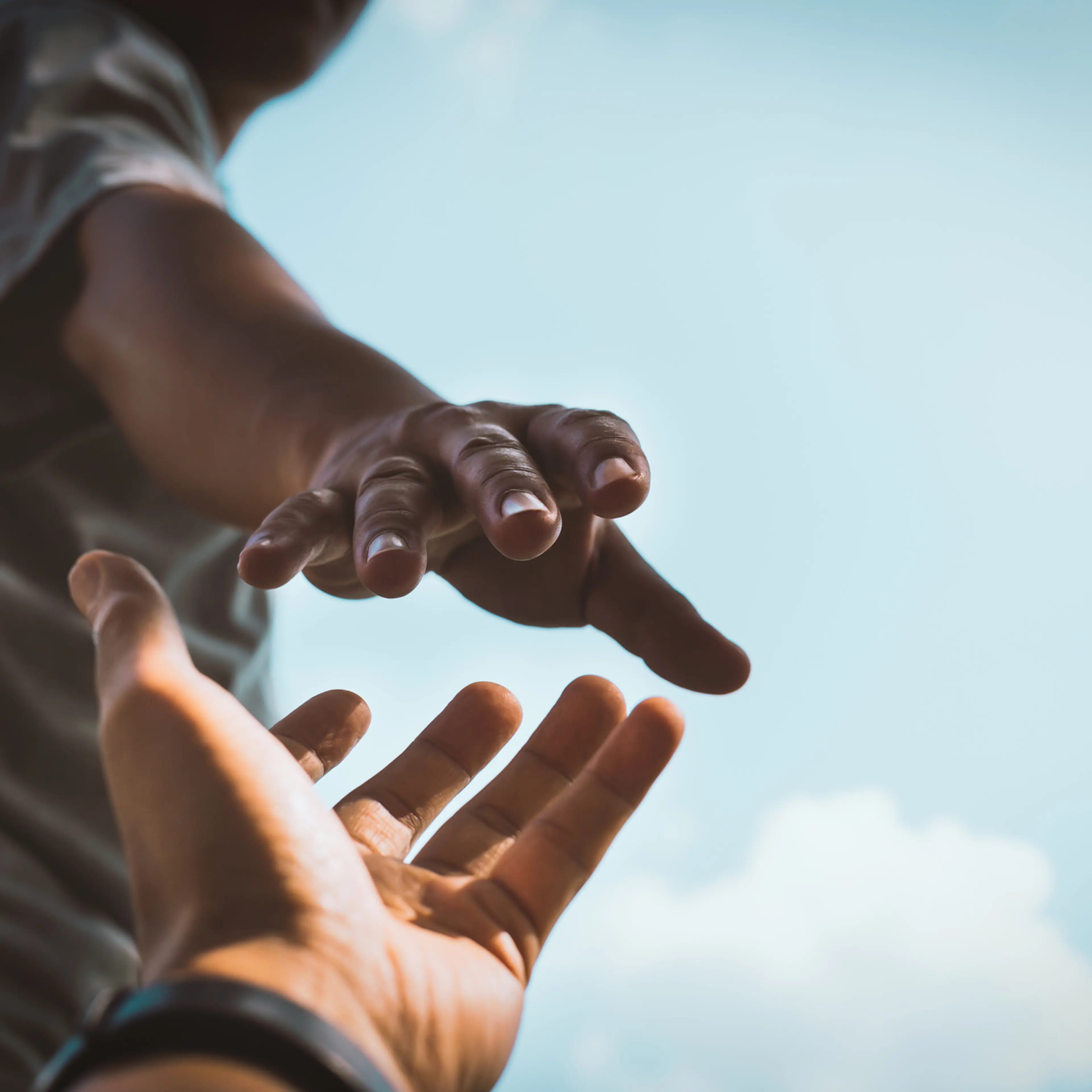 Cropped hands reaching out to help each other against sky,Thailand