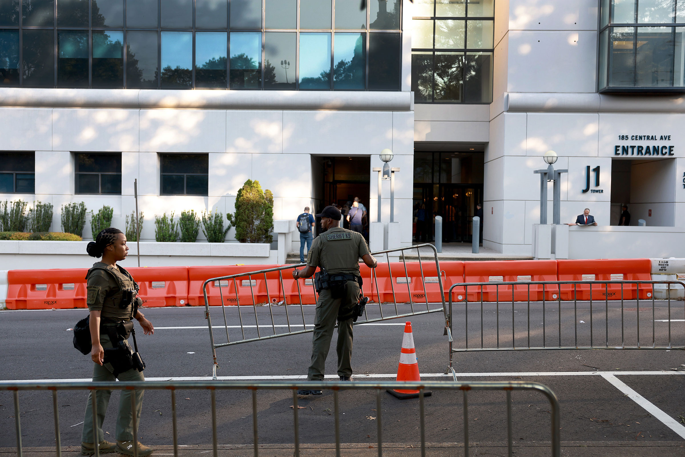 Fulton County Sheriff officers move mental fences into place in front of one of the entrances to the Fulton County Courthouse