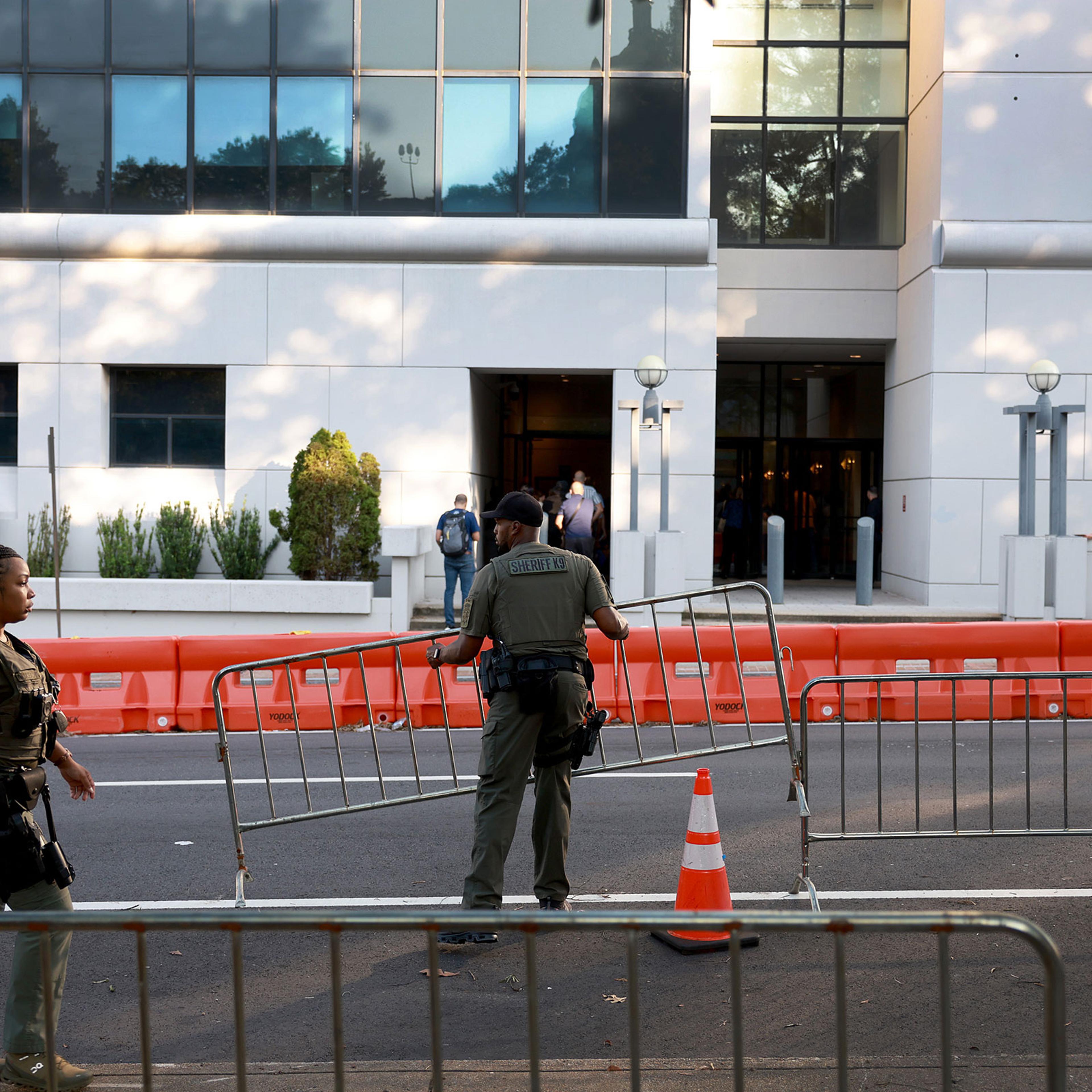 Fulton County Sheriff officers move mental fences into place in front of one of the entrances to the Fulton County Courthouse